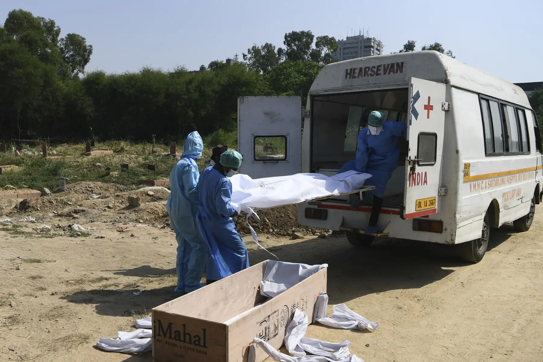 Los trabajadores del cementerio llevan el cadáver de una víctima que murió por el coronavirus, en Nueva Delhi. Foto: AFP
