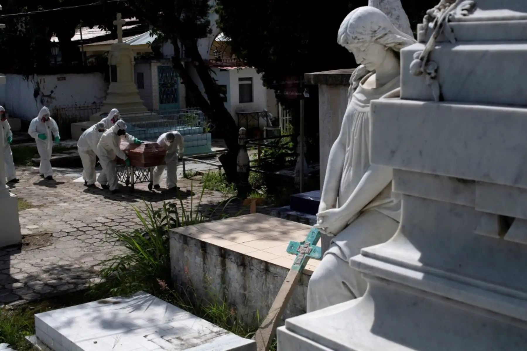 Sepultureros del cementerio municipal de Santa Tecla, vestidos con trajes de bioseguridad, cargan el ataúd de una víctima del coronavirus, en El Salvador. Foto:AFP