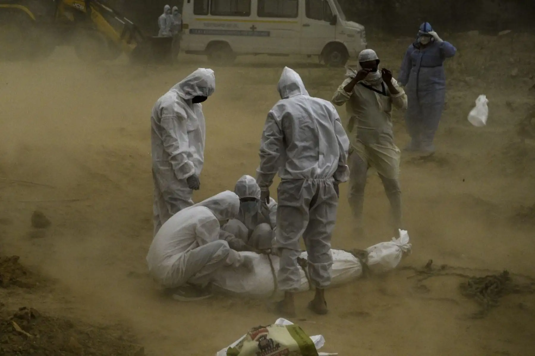 Familiares cubiertos con equipo de bioseguridad atan el cadáver de una víctima de covid-19 antes del entierro en un cementerio de Nueva Delhi. Foto: AFP