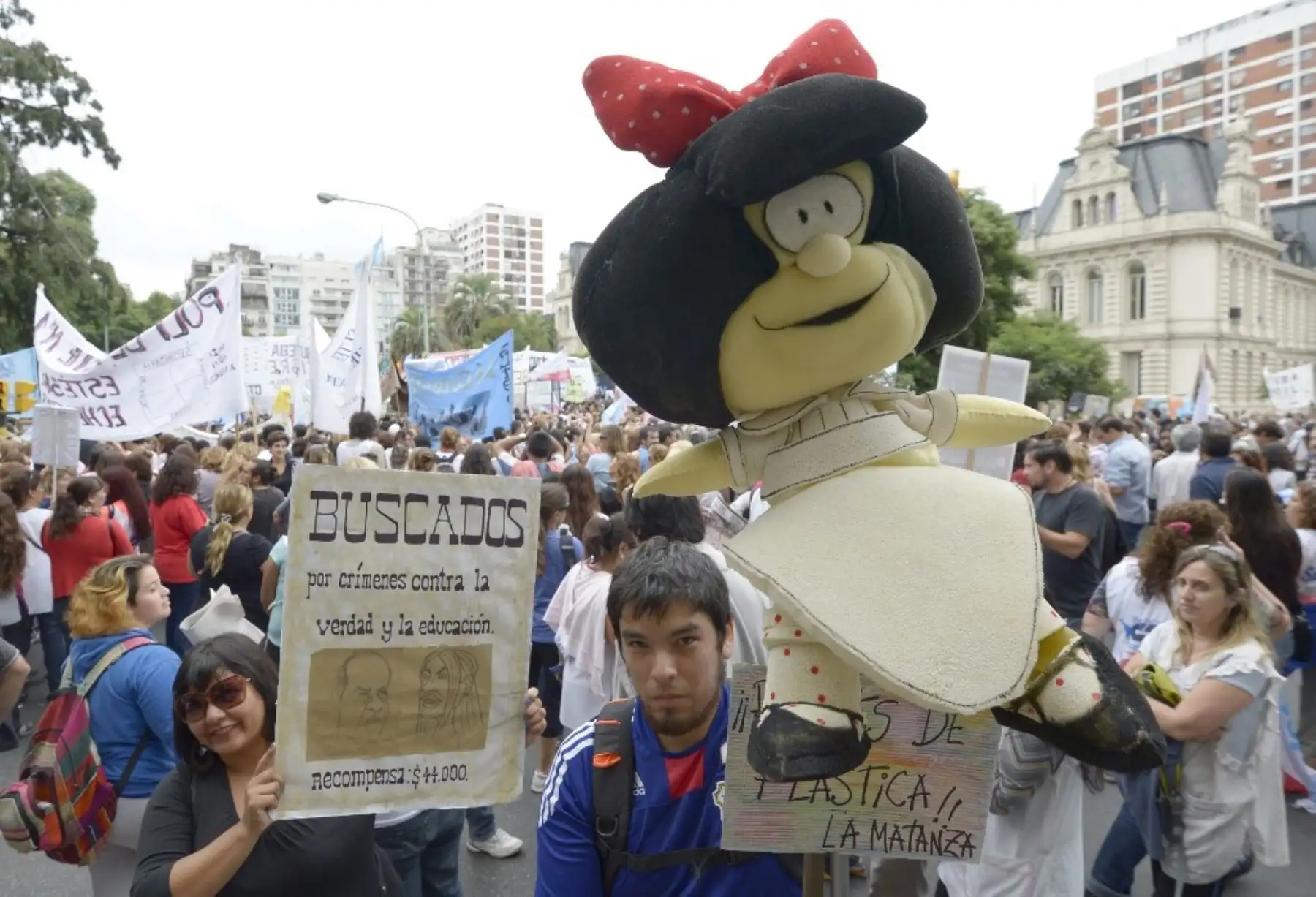 Un hombre sostiene un muñeco de Mafalda, durante una manifestación de maestros, que exige aumento de sueldo frente al Ministerio de Educación, en Buenos Aires, el 26 de marzo de 2014. Foto: AFP