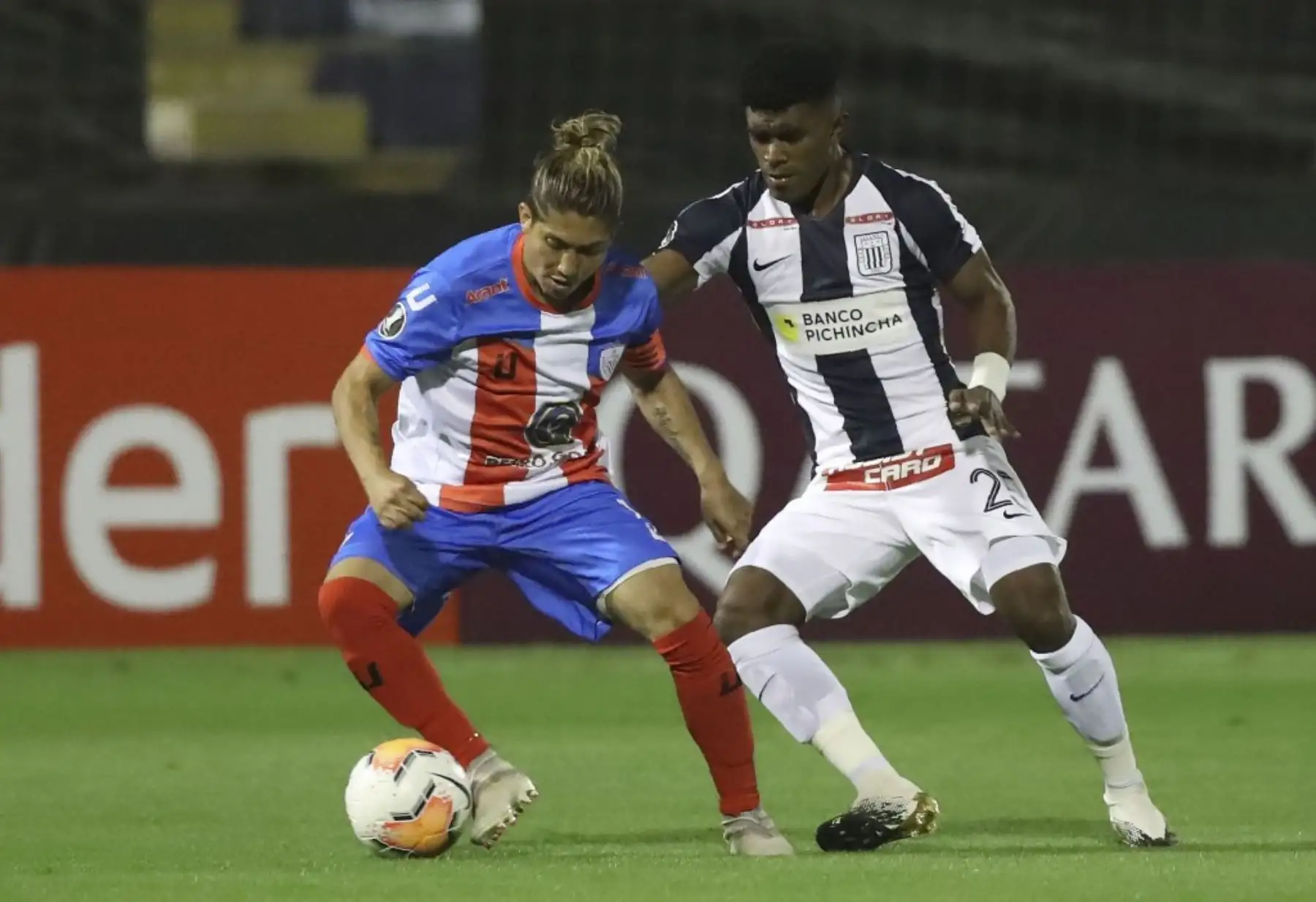 El mediocampista de Estudiantes de Mérida de Venezuela, Jesús Meza (izq.), Y el mediocampista de Alianza Lima de Perú, Oslimg Mora, compiten por el balón durante el partido de fútbol a puerta cerrada de la fase de grupos de la Copa Libertadores en el Estadio Alejandro Villanueva.

Foto: AFP