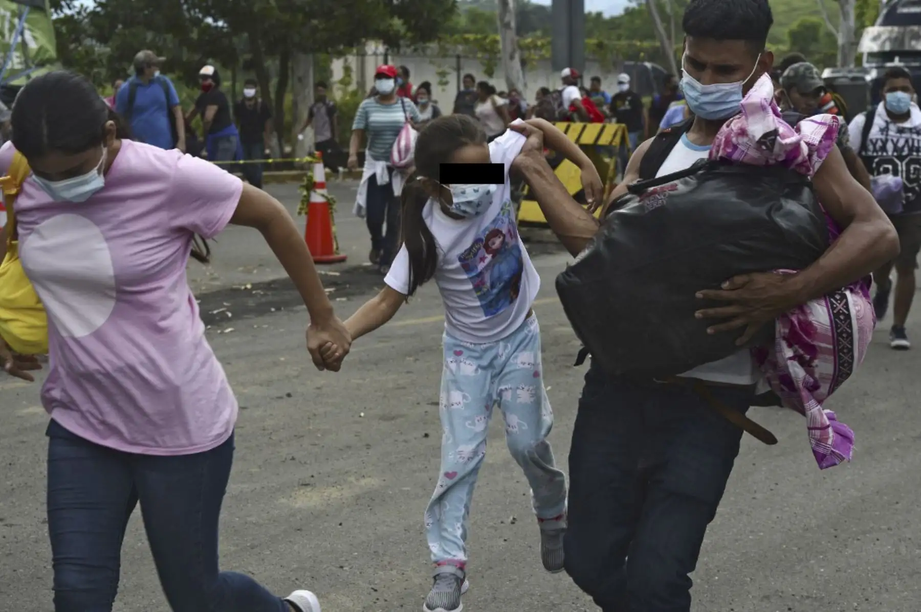 Una pareja de migrantes hondureños y su hija atraviesan una cerca policial para ingresar a Guatemala en su camino a los Estados Unidos, en la frontera de Corinto, Honduras. Foto: AFP