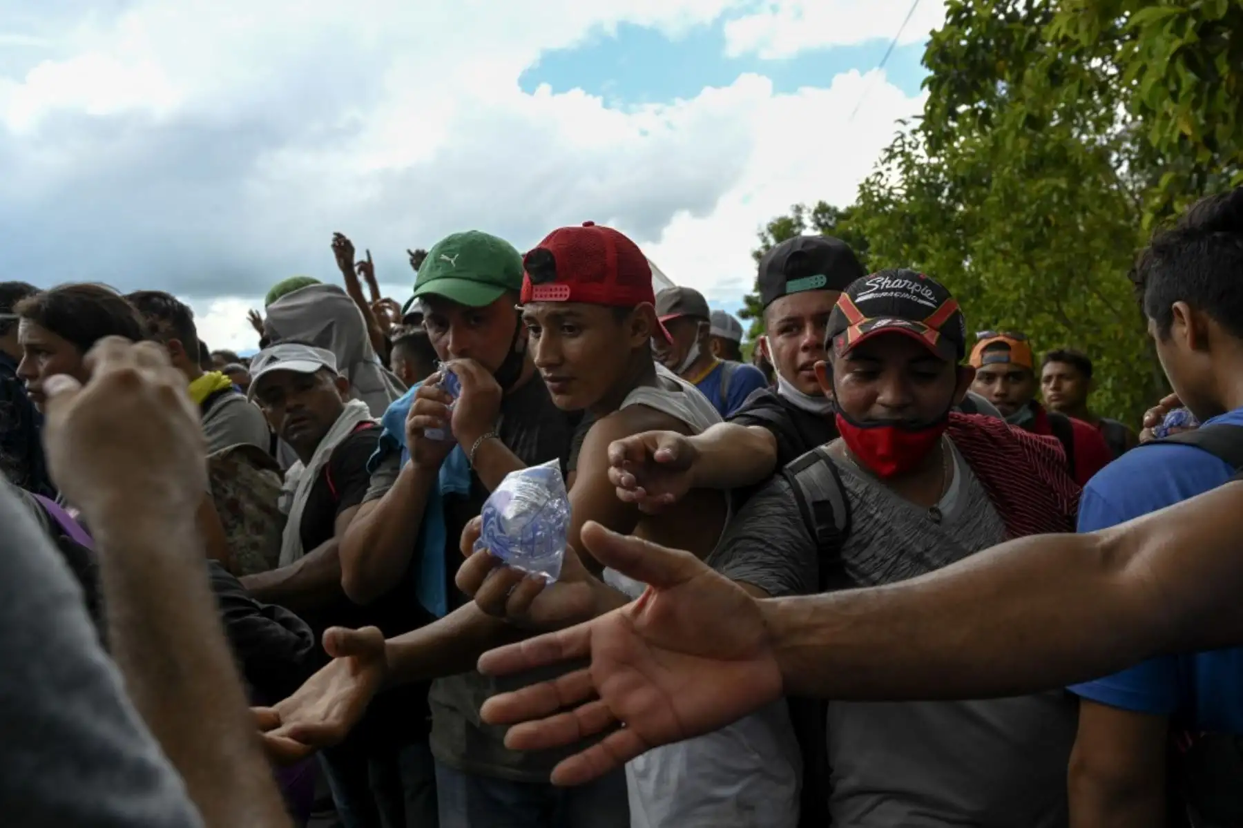 Migrantes hondureños, parte de una caravana rumbo a Estados Unidos, buscan agua que les entregan miembros del Ejército de Guatemala, en Entre Ríos, Guatemala, luego de cruzar la frontera de Honduras. Foto: AFP