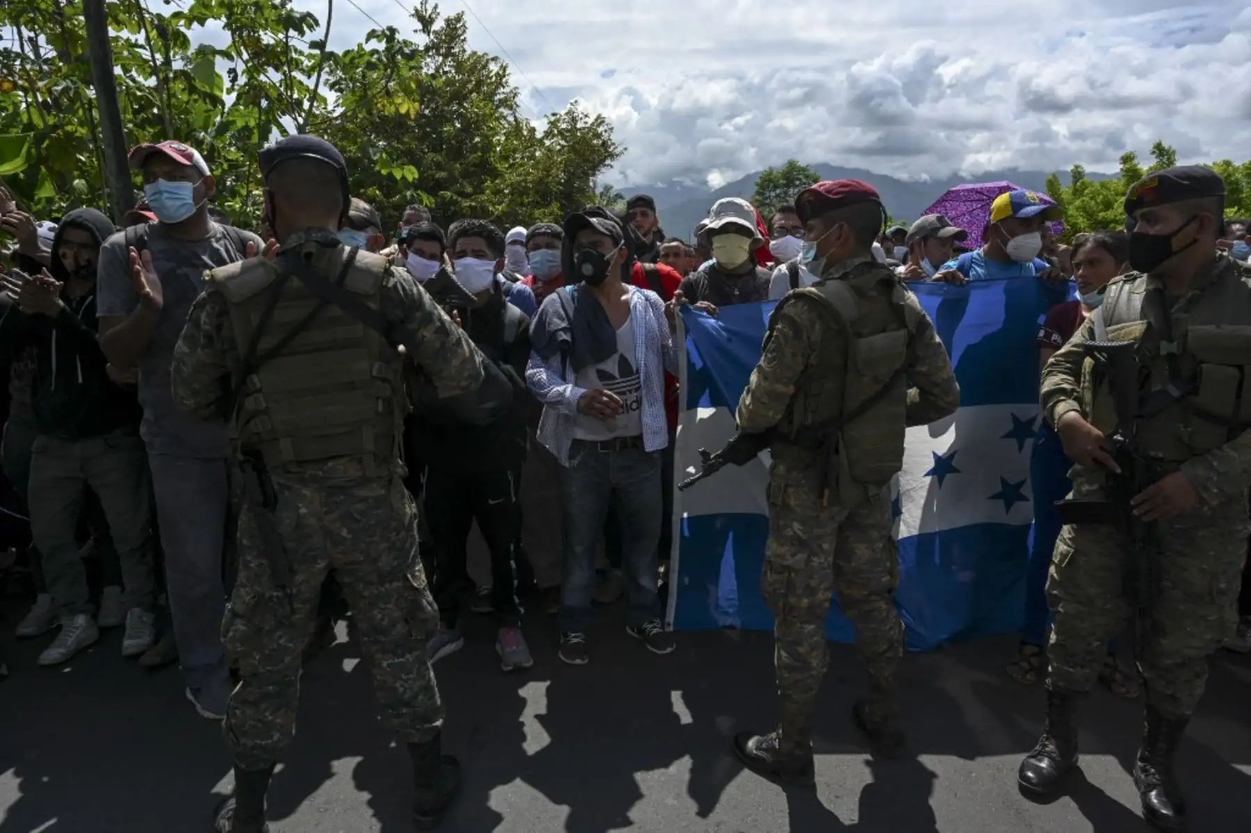 Miembros del Ejército de Guatemala detienen a un grupo de migrantes hondureños que portaban una bandera hondureña en Entre Ríos, Guatemala, después de que cruzaron la frontera de Honduras en su camino a los EE. UU. Foto: AFP