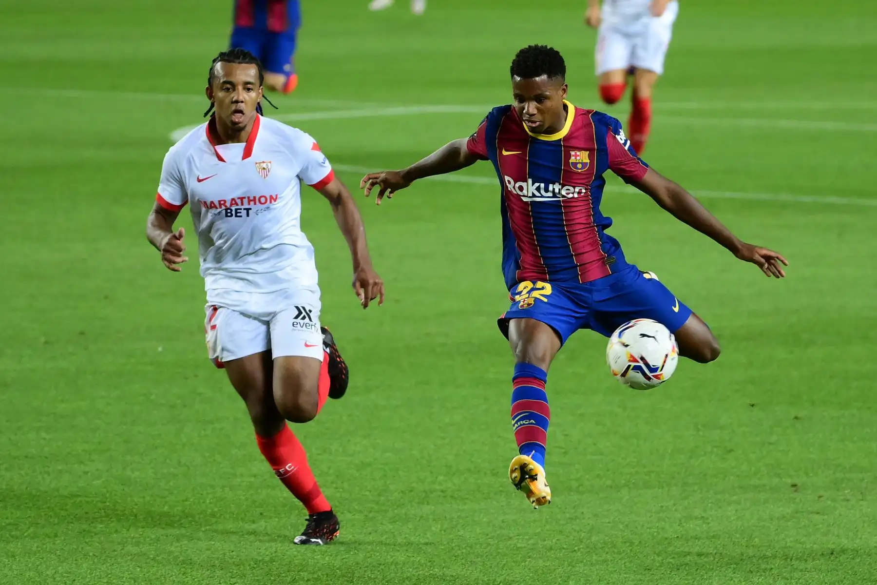 El defensor francés del Sevilla, Jules Kounde, desafía al mediocampista español del Barcelona, Ansu Fati, durante el partido de fútbol de la Liga española. Foto: AFP
