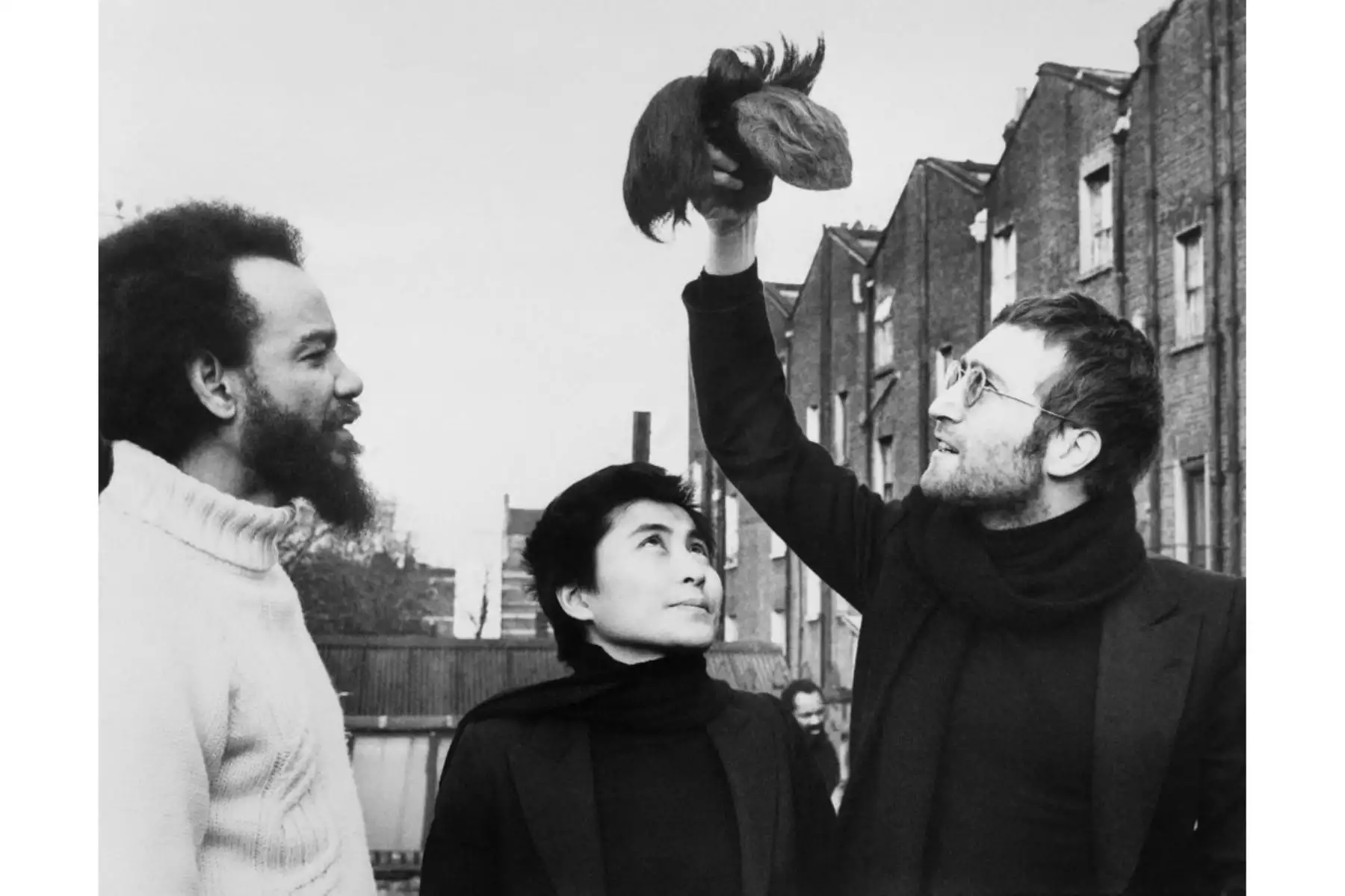 El cantante británico John Lennon, ex miembro de The Beatles y su esposa Yoko Ono, le dan mechones de cabello al activista Michael de Freitas, alias Michael X el 13 de mayo de 1971 en Londres. Foto: AFP