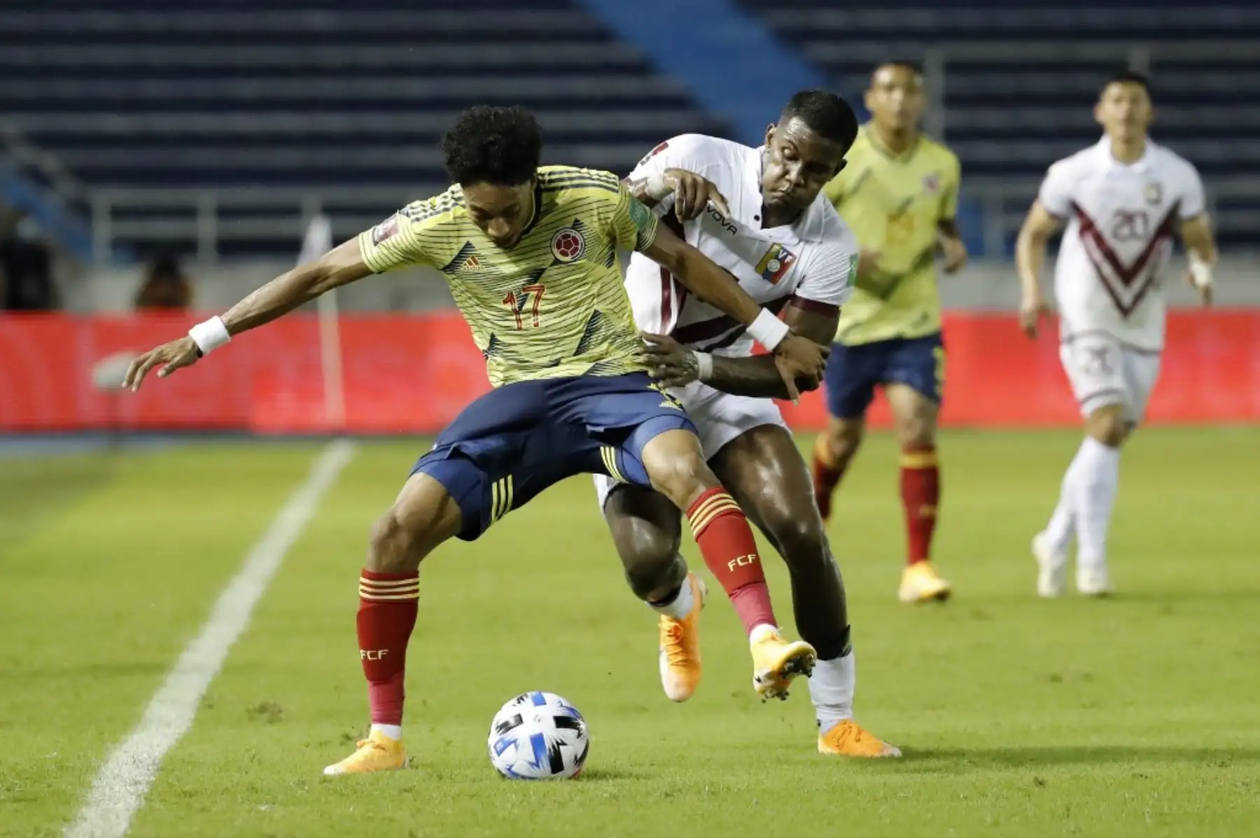 El colombiano Johan Mojica (izq.) Y el venezolano Sergio Cordova compiten por el balón durante su partido de fútbol clasificatorio sudamericano para la Copa Mundial de la FIFA 2022 en el Estadio Metropolitano Roberto Meléndez en Barranquilla, Colombia. Foto: AFP