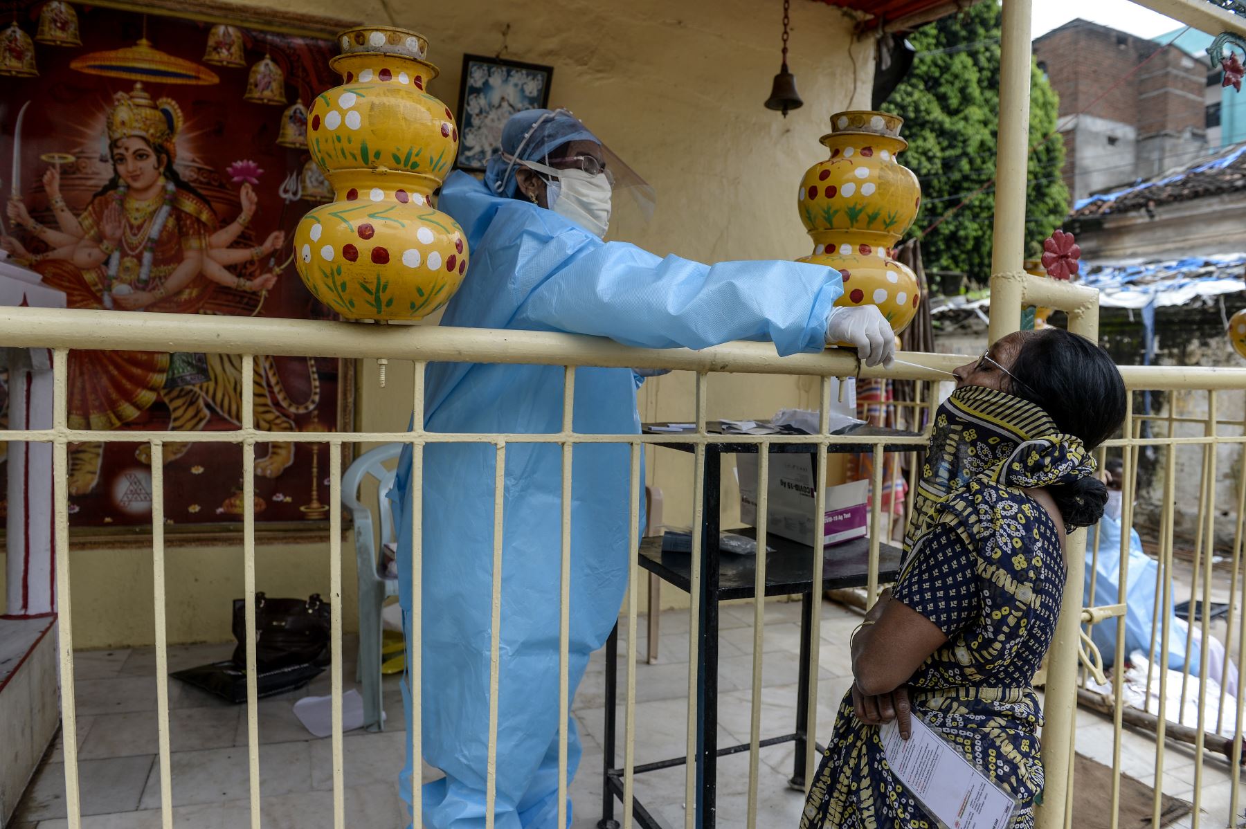 Un trabajador de salud toma una muestra de hisopo para detectar el Covid-19 en una mujer de Hyderabad, en la India. Foto: AFP