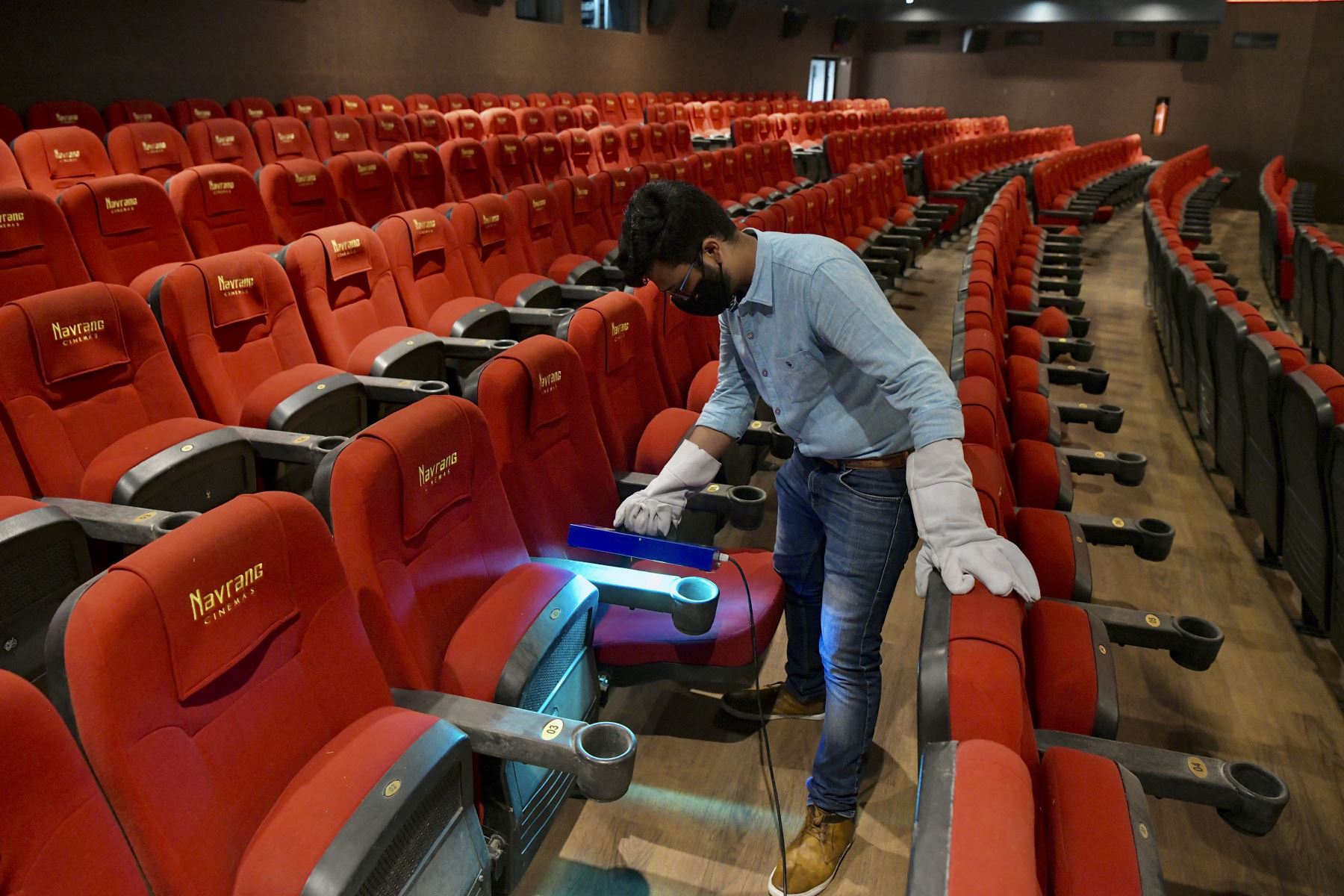 Un trabajador explica el proceso de esterilización en las salas de cine a través de un dispositivo de luz ultravioleta, en Bangalore. Las empresas de cine se preparan para reabrir el próximo 15 de octubre al 50%. Foto: AFP