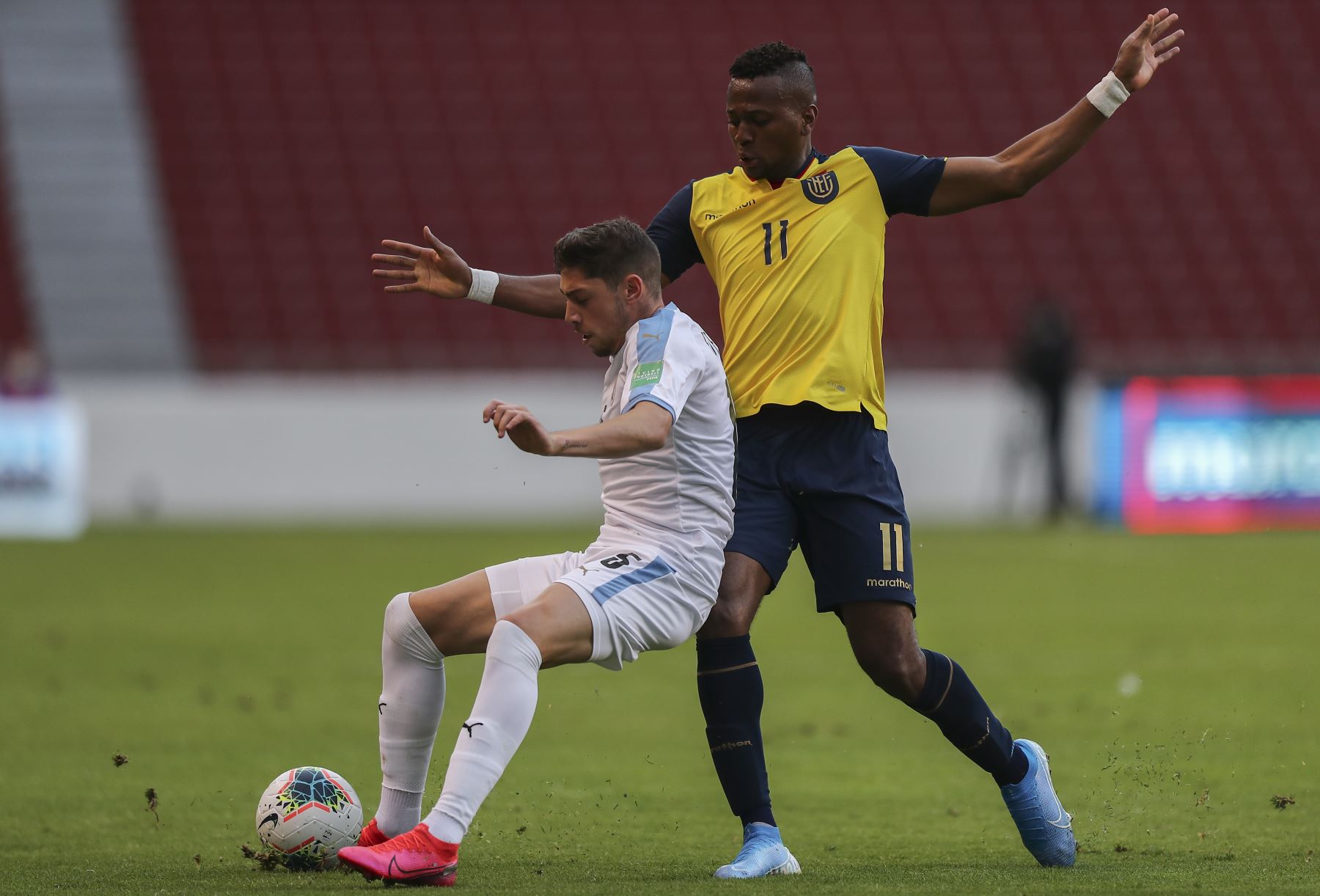 El ecuatoriano Michael Estrada y el uruguayo Mauro Arambarri compiten por el balón durante partido por Clasificatorias Qatar 2022, en el Estadio Rodrigo Paz Delgado, en Quito. Foto: AFP