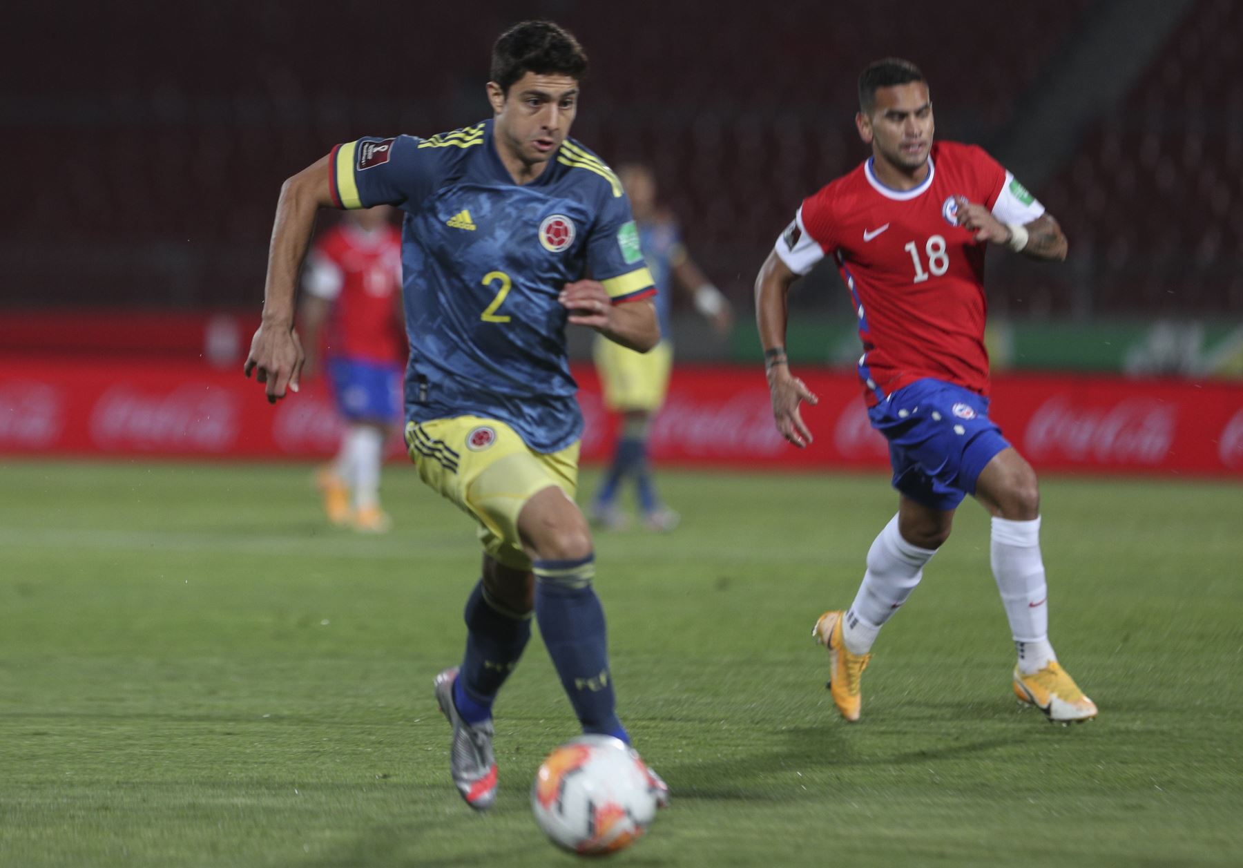 El colombiano Stefan Medina y el chileno Sebastian Vegas compiten por el balón durante partido por Clasificatorias Qatar 2022, en el Estadio Nacional de Santiago. Foto: AFP