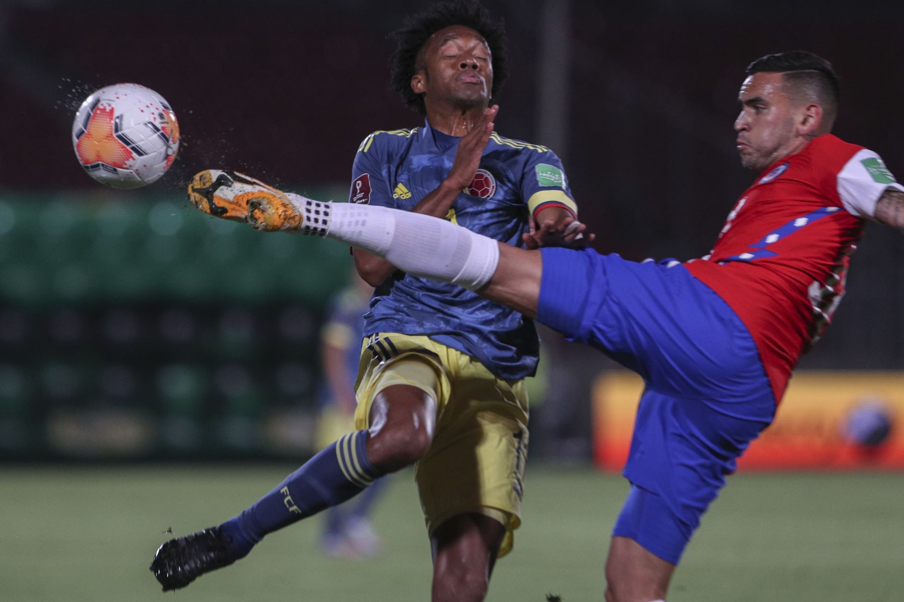 El colombiano Juan Guillermo Cuadrado y el chileno Sebastian Vegas compiten por el balón durante partido por Clasificatorias Qatar 2022, en el Estadio Nacional de Santiago. Foto: AFP