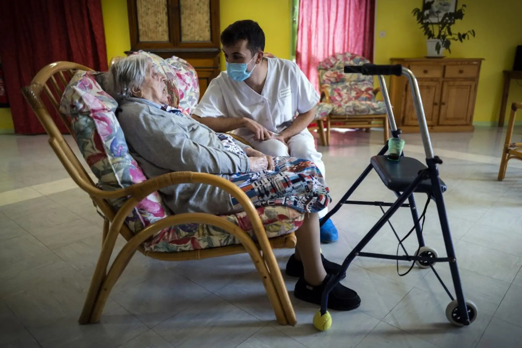 Rosalie Jalbert, de 102 años, que dio positivo en la prueba del Covid-19, conversa con un empleado mientras se sienta en un sofá en la casa de retiro Le Coustil en Salles, sur de Francia. Foto: AFP