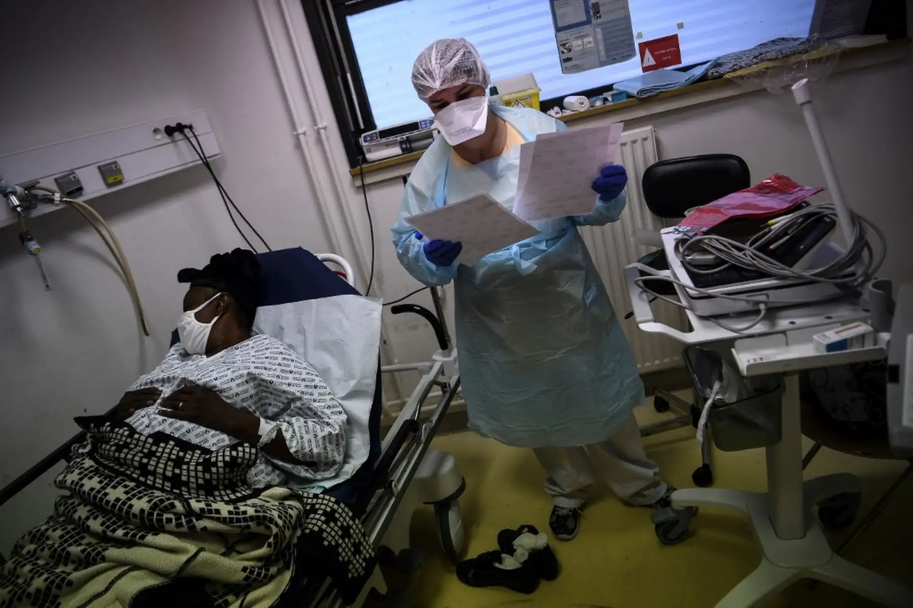 Una enfermera revisa los documentos mientras está de pie junto a una mujer que yace en una cama y se sospecha que está infectada con Covid-19 en el servicio de emergencia del hospital Andre Gregoire en Montreuil, al este de París. Foto: AFP