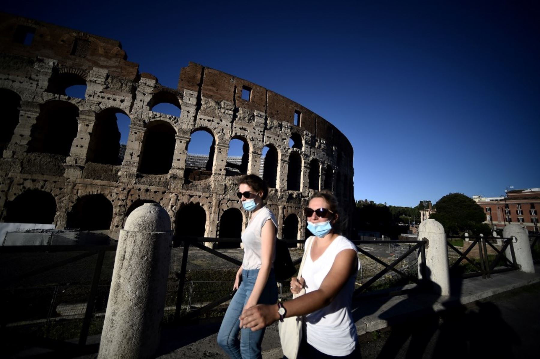 Personas con mascarillas caminan por el antiguo Coliseo en el centro de Roma. Foto: AFP