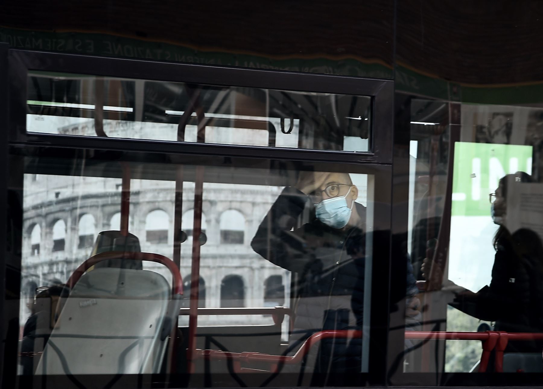 Un viajero con una mascarilla se para en un autobús junto al Coliseo en medio de la pandemia de Covid-19 en el centro de Roma. Foto: AFP