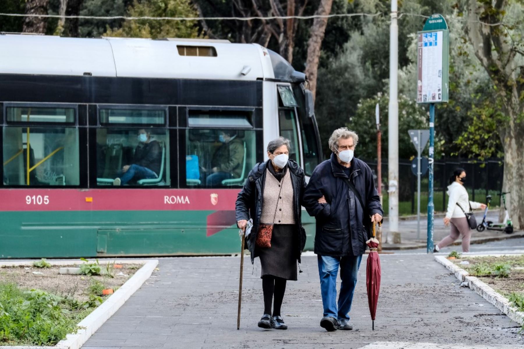 Una pareja de ancianos con mascarillas protectoras, se aleja de la parada del tranvía en medio de la pandemia Covid-19, en Roma. Foto: AFP