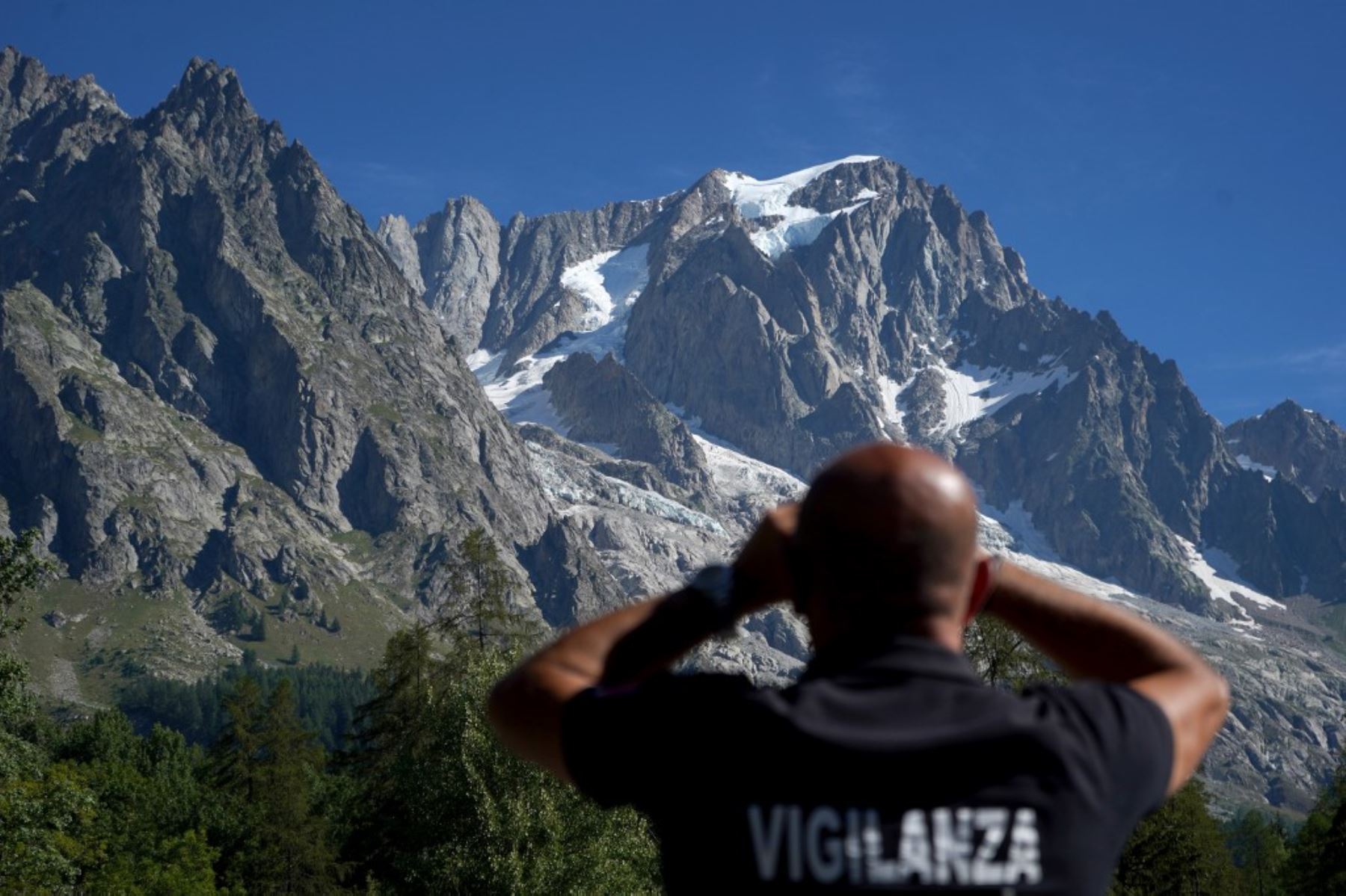 Un oficial de seguridad mira a través de binoculares el glaciar Planpincieux en el pueblo de Courmayeur, Val Ferret, noroeste de Italia. Foto: AFP