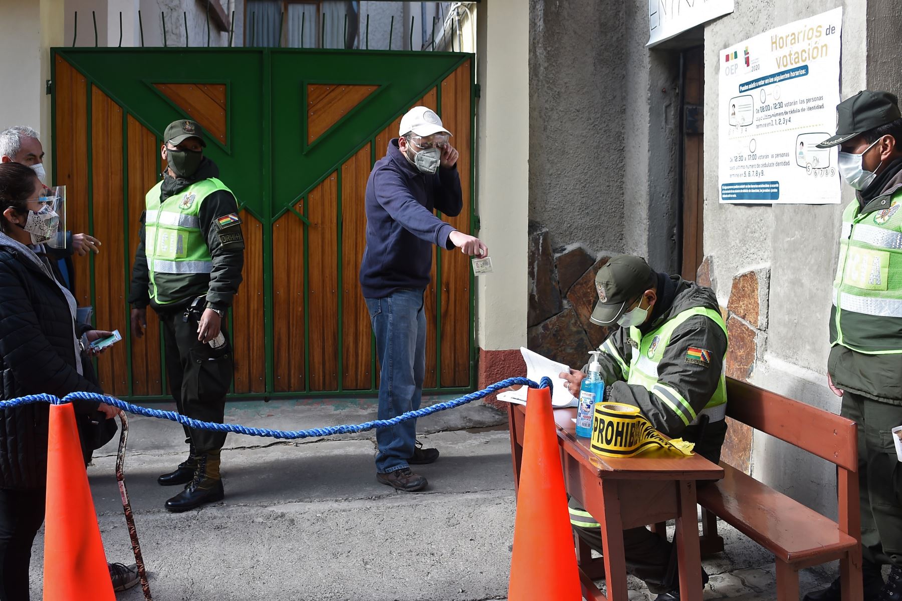 Un hombre muestra su cédula de identidad a un oficial de policía para poder ingresar a un colegio electoral en La Paz. Foto. AFP