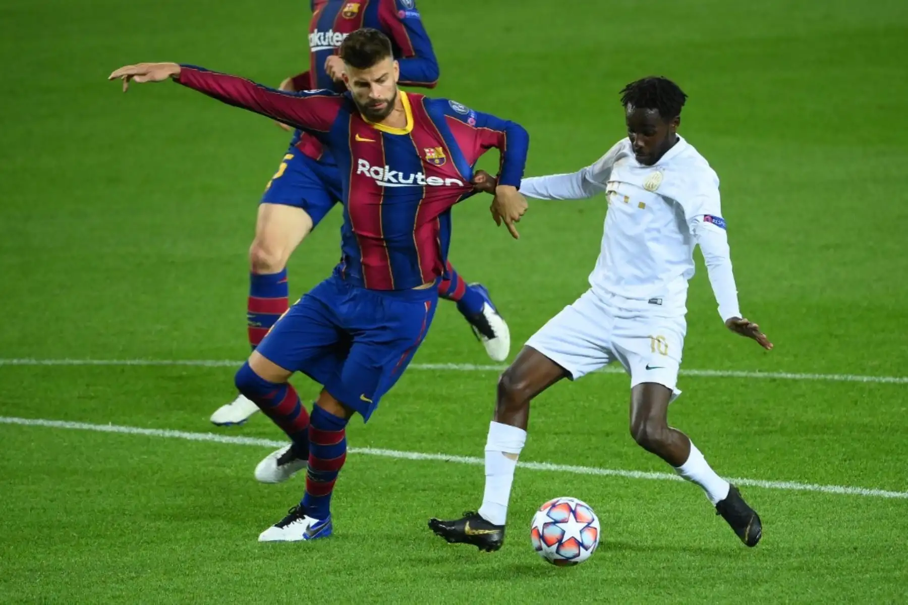 El defensa español del Barcelona, Gerard Piqué (izq.), Compite con el mediocampista noruego de Ferencvaros, Tokmac Nguen, durante el partido de fútbol de la UEFA Champions League entre el FC Barcelona y el Ferencvarosi TC en el estadio Camp Nou de Barcelona. Foto: AFP