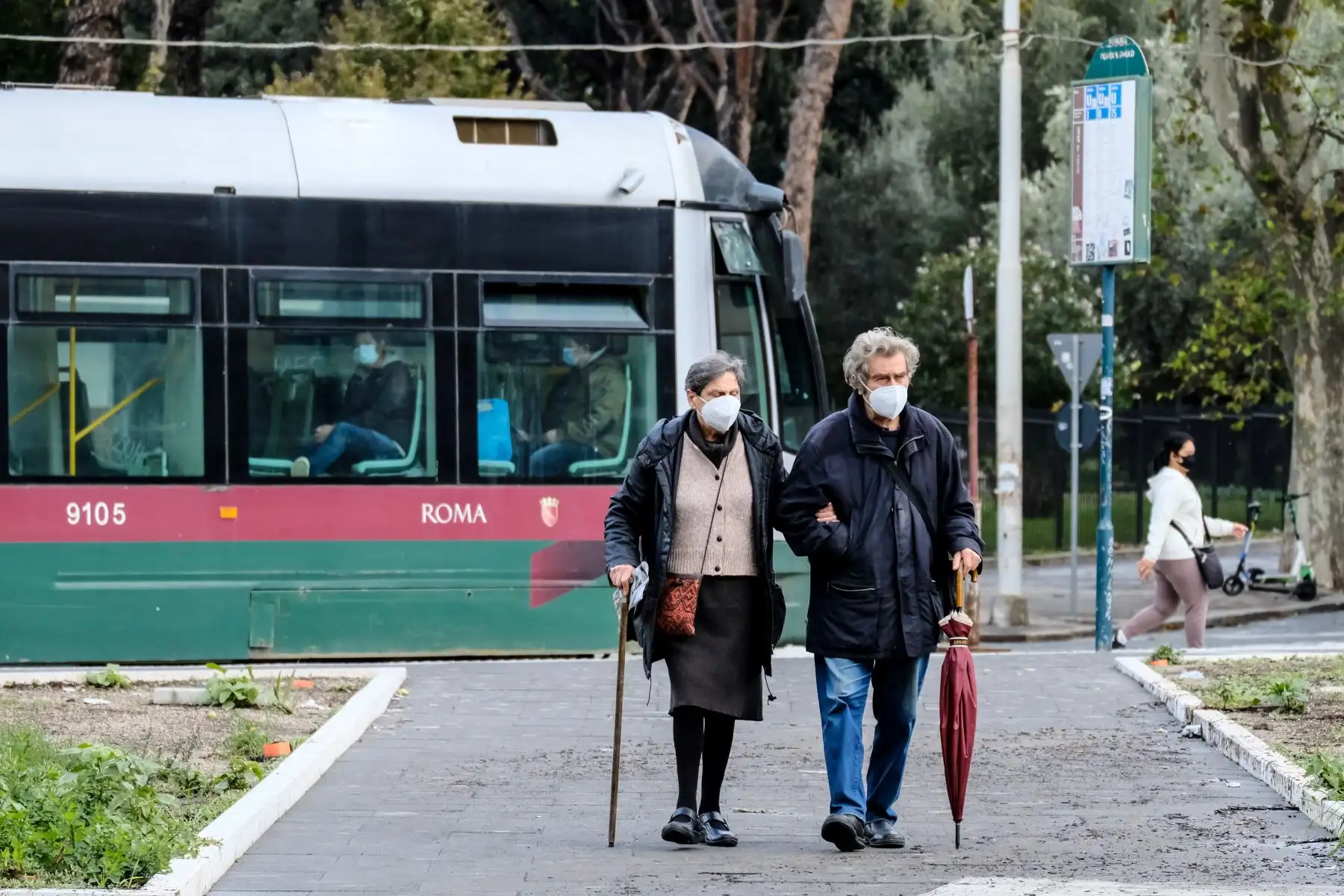 Una pareja de ancianos con mascarillas protectoras, se aleja de la parada del tranvía en medio de la pandemia, en Roma. Foto: AFP