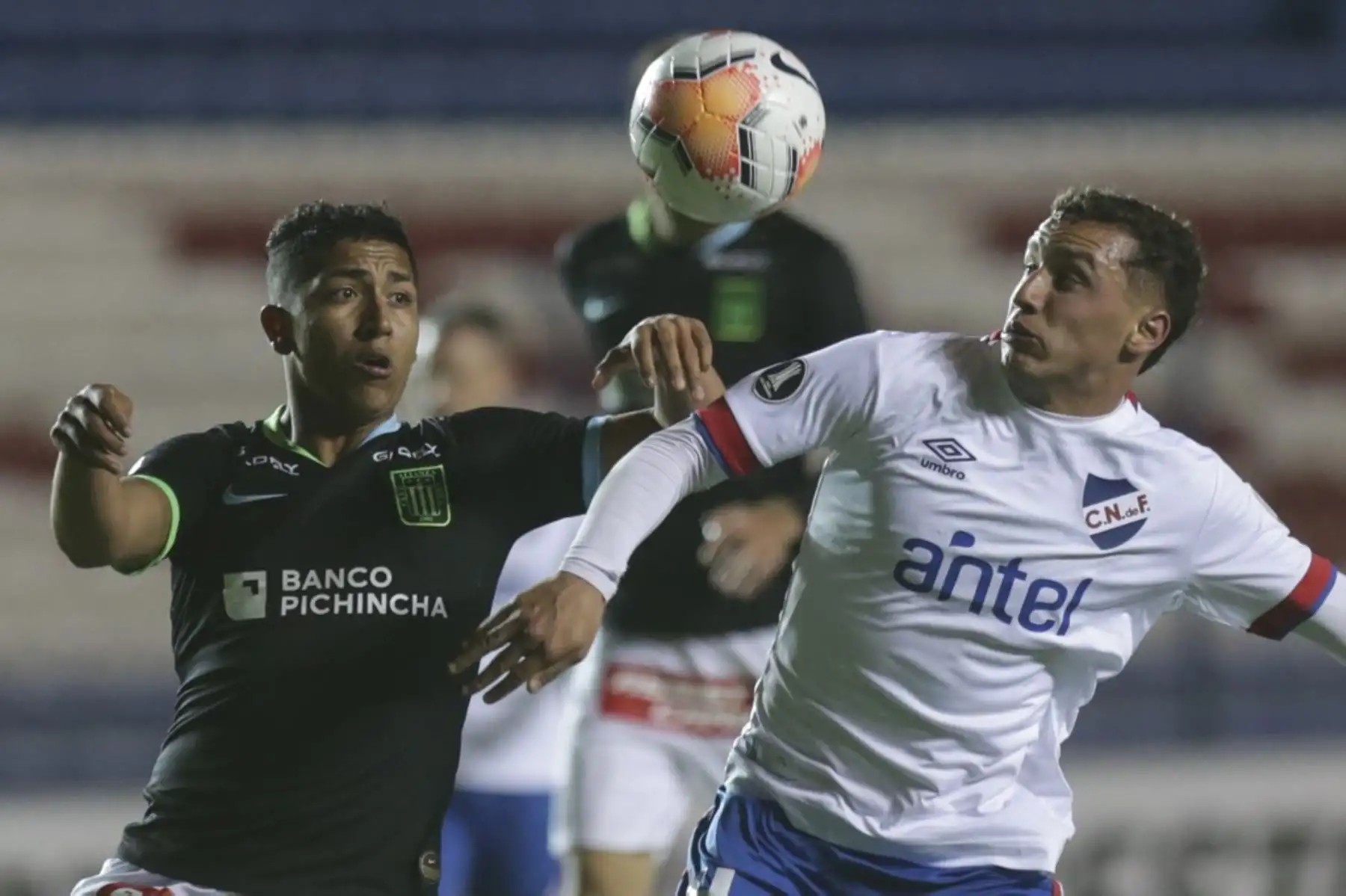 El defensa peruano de Alianza Lima Carlos Montoya y el mediocampista Nacional de Uruguay Joaquín Trasante disputan el balón durante su partido de fútbol a puerta cerrada en la fase de grupos de la Copa Libertadores en el Estadio Gran Parque Central de Montevideo. Foto: AFP