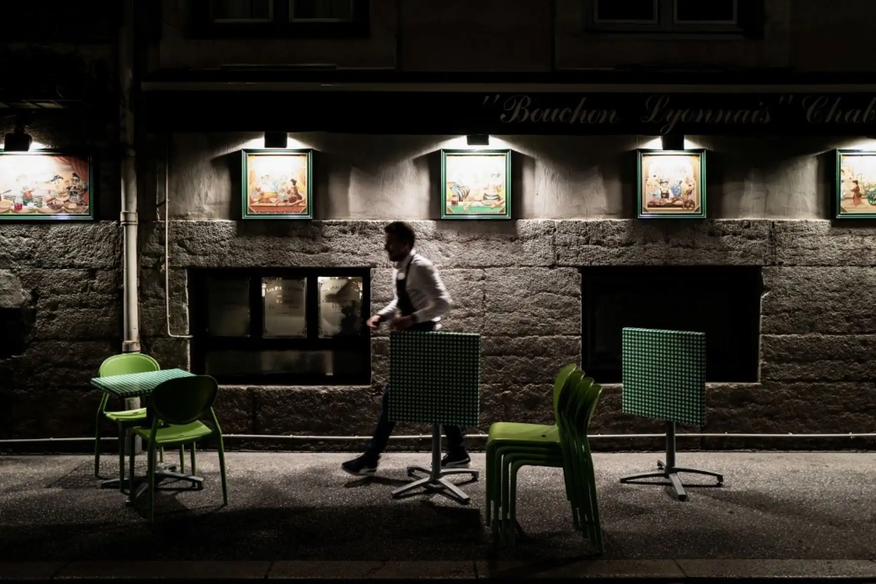 Un empleado de un restaurante cierra su terraza unos minutos antes del inicio del toque de queda para combatir la propagación del covid-19. Foto: AFP