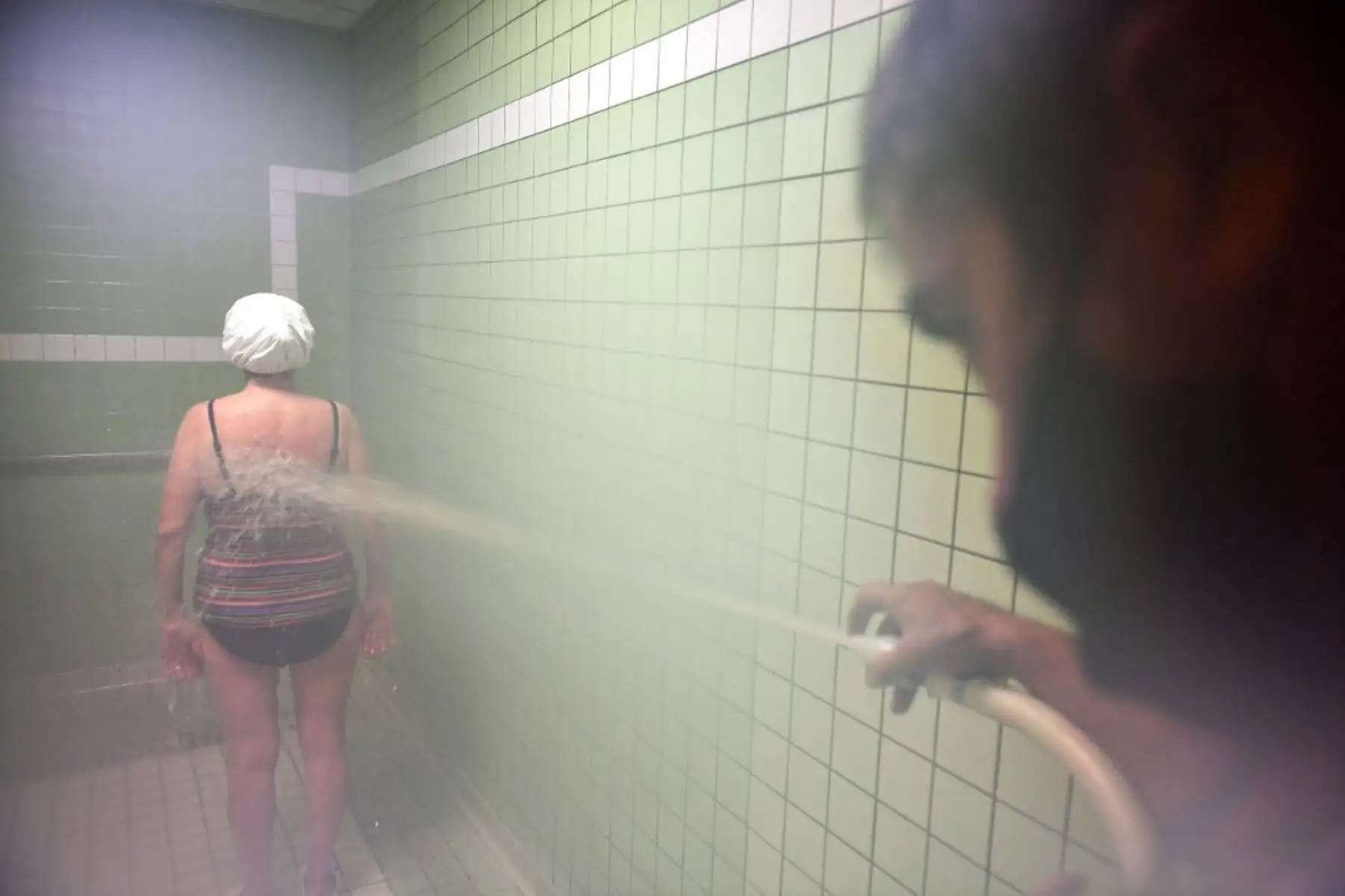 Un cliente de terapia recibe un chorro de ducha de un empleado de un baño termal que lleva una máscara protectora en los baños termales de Luchon en Bagneres-de-Luchon. Foto: AFP