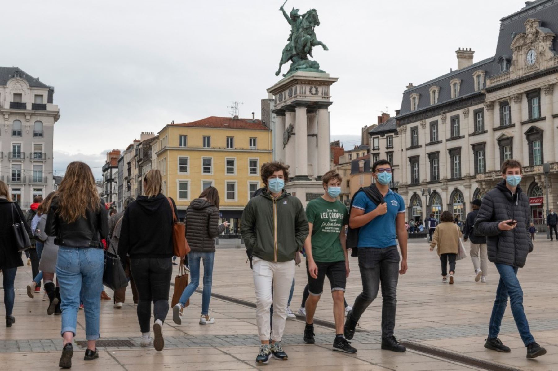 Personas, con máscaras faciales, caminan por la Place de Jaude en Clermont-Ferrand, mientras el primer ministro francés celebra una conferencia de prensa sobre las restricciones del covid-19. Foto: AFP
