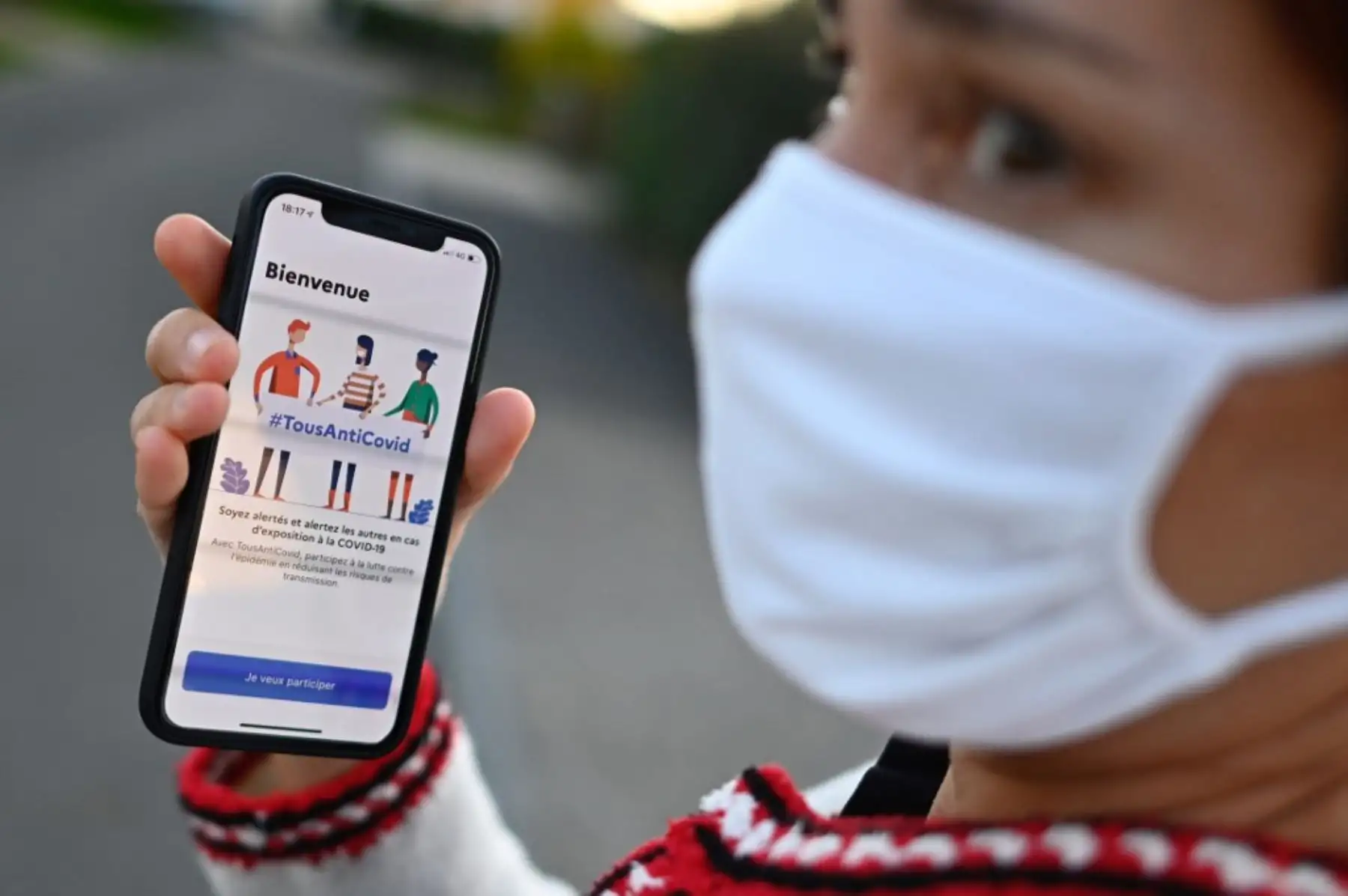 Una mujer con una máscara facial sostiene un teléfono inteligente que muestra la nueva aplicación "TousAntiCovid" en Rennes, en el oeste de Francia. Foto: AFP