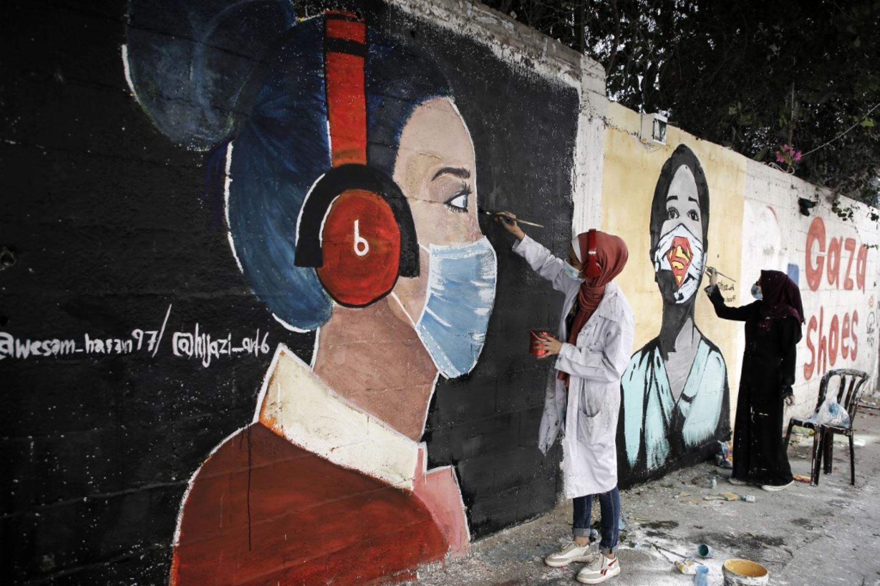 Estudiantes palestinos pintan murales de niñas vestidas con máscaras en la ciudad de Gaza el 22 de octubre de 2020, en medio de la nueva crisis pandémica del coronavirus. Foto: AFP