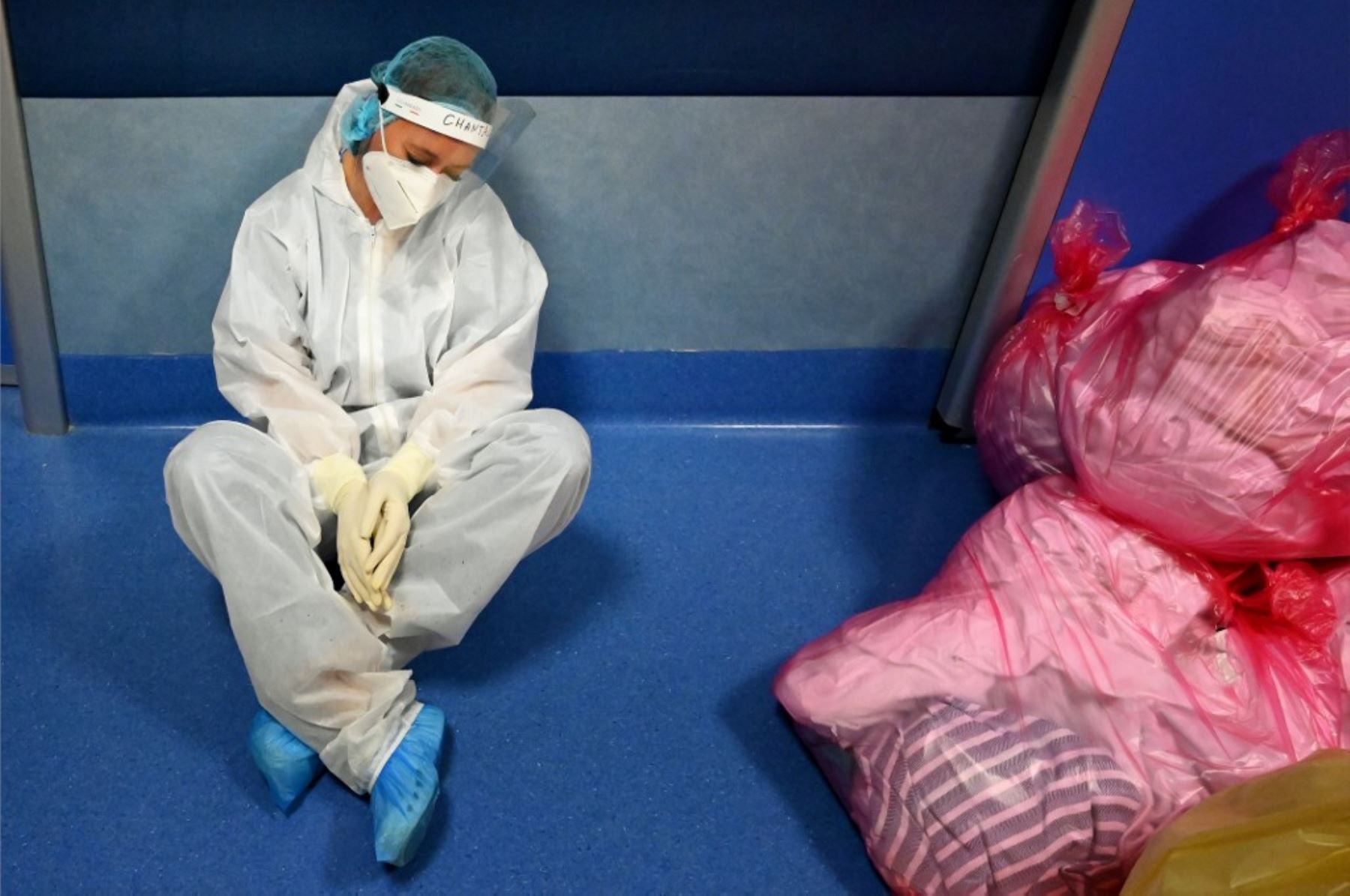 Un trabajador médico con equipo de protección personal (PPE) se sienta en el piso descansando en la Unidad de Cuidados Intensivos (UCI) de nivel COVID 3 para casos de nuevo coronavirus, COVID-19, en el hospital Casal Palocco, cerca de Roma. Foto: AFP