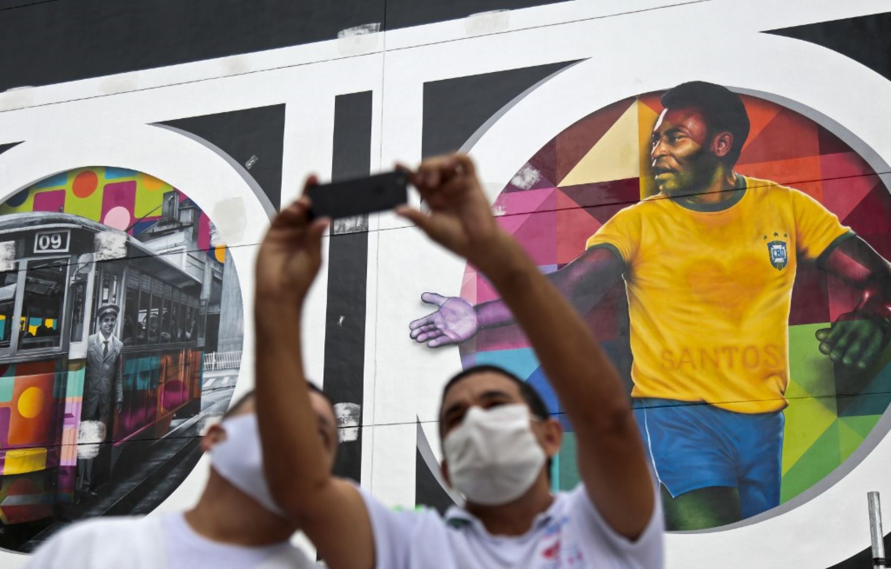 Los hombres se toman una selfie con un mural del artista brasileño Kobra que representa a la estrella del fútbol brasileño retirado Edson Arantes do Nascimento, conocido como Pele. Foto: AFP