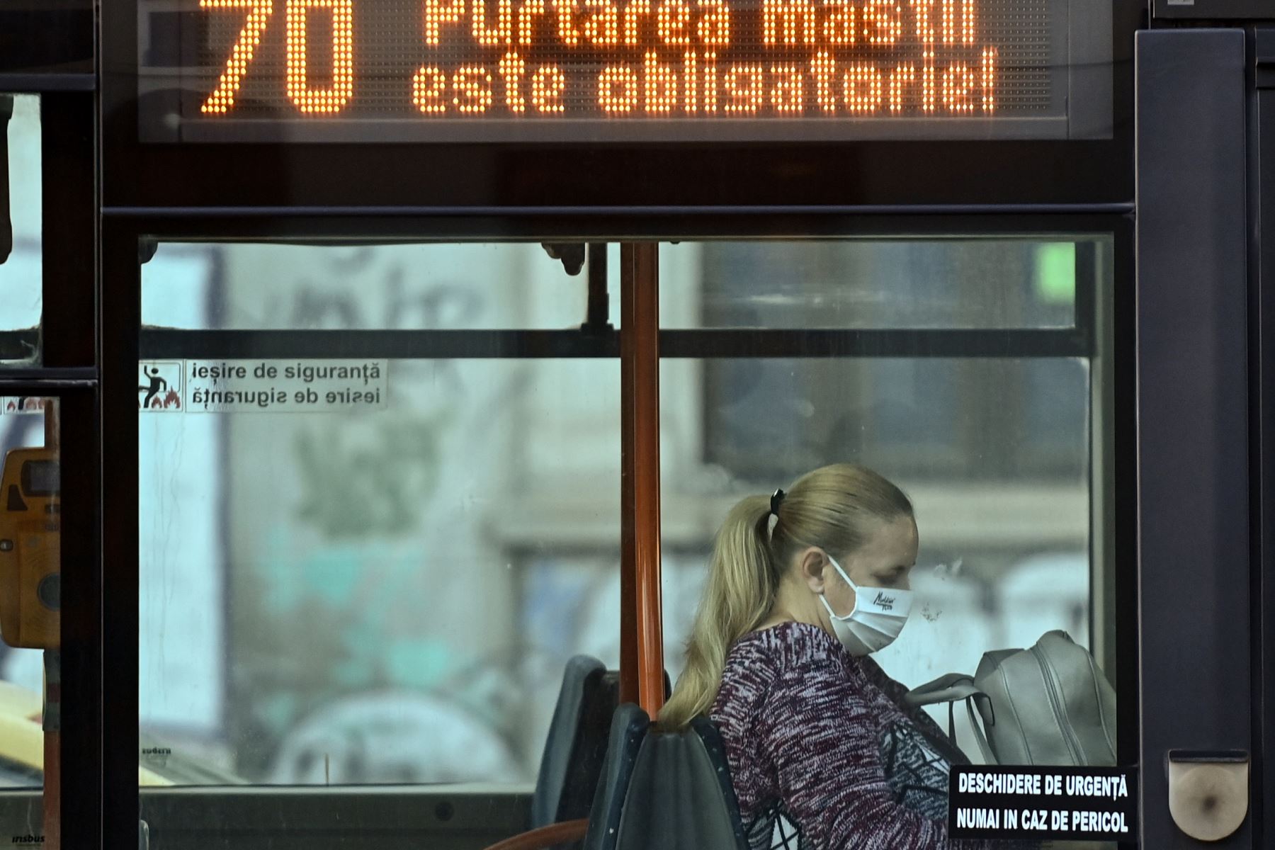 Una mujer que usa una máscara facial de protección viaja en un autobús en Bucarest, Rumania. La capital de Rumania, Bucarest, decidió el 22 de octubre de 2020 cerrar escuelas y cines, y hacer que el uso de máscaras en los espacios públicos sea obligatorio a partir del martes. 

Foto: EFE