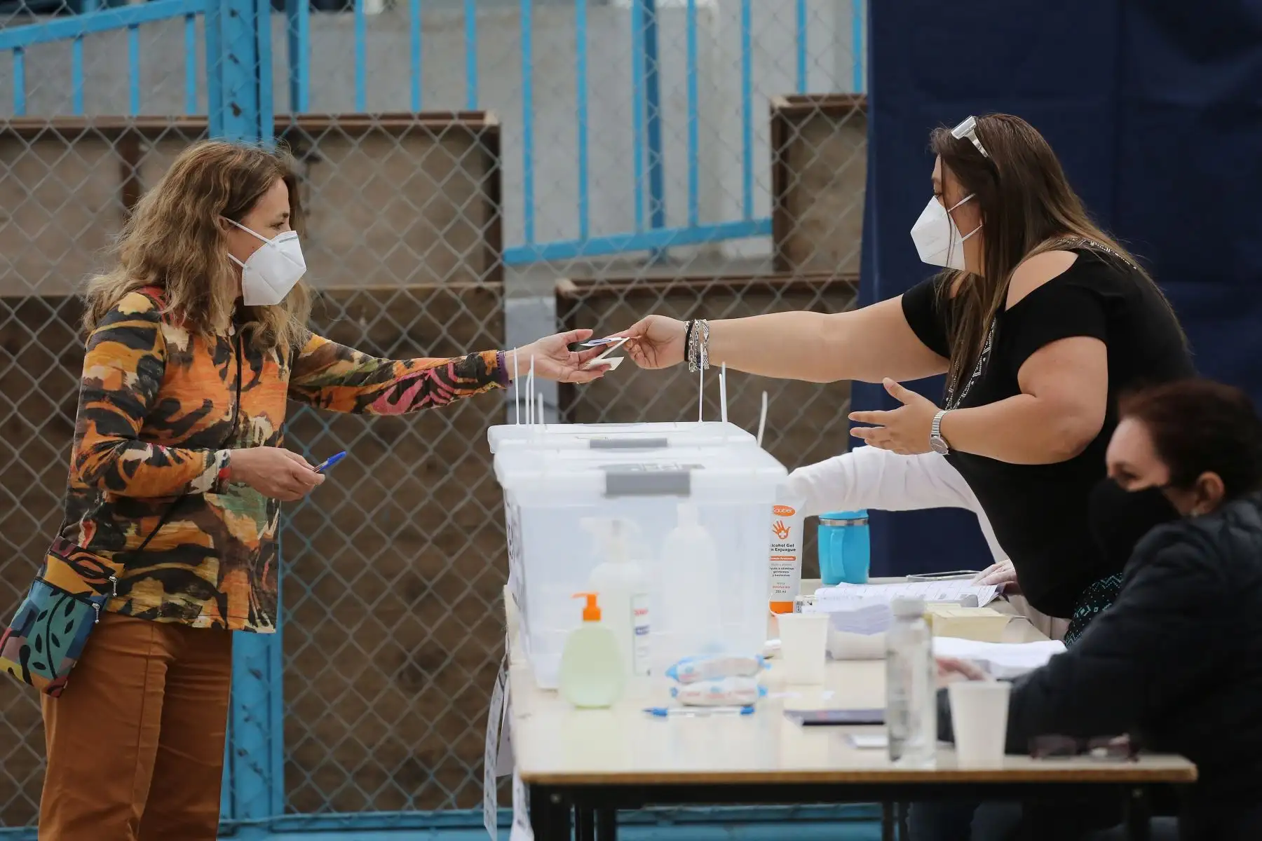 Una mujer recibe la papeleta de votación para ejercer su voto por el plebiscito constitucional, en un colegio electoral, este domingo, en Santiago de Chile. Foto: EFE