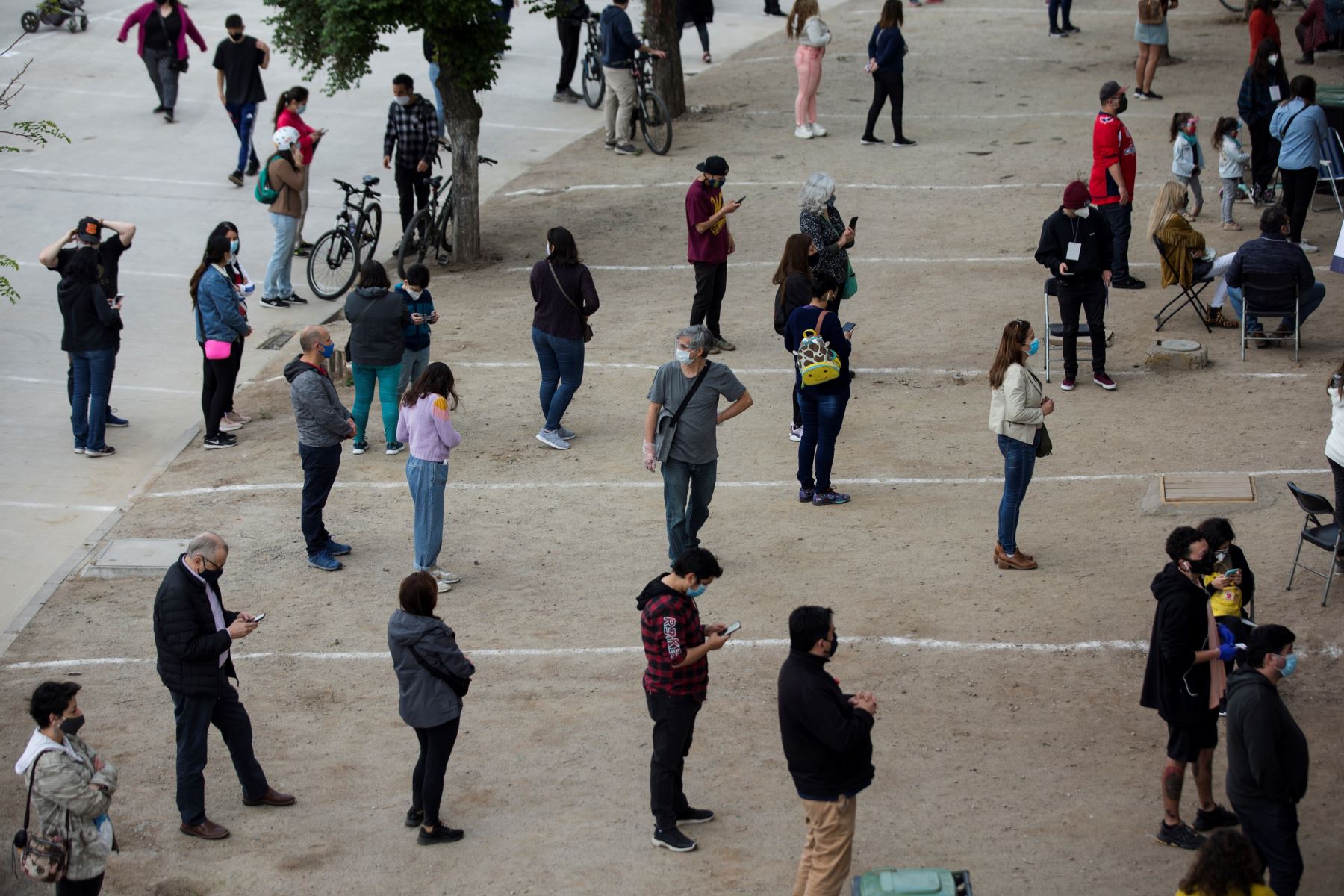 Ciudadanos mantienen la distancia social mientras esperan entrar al Estadio Nacional para ejercer su voto del plebiscito constitucional, este domingo, en Santiago de Chile. Foto: EFE