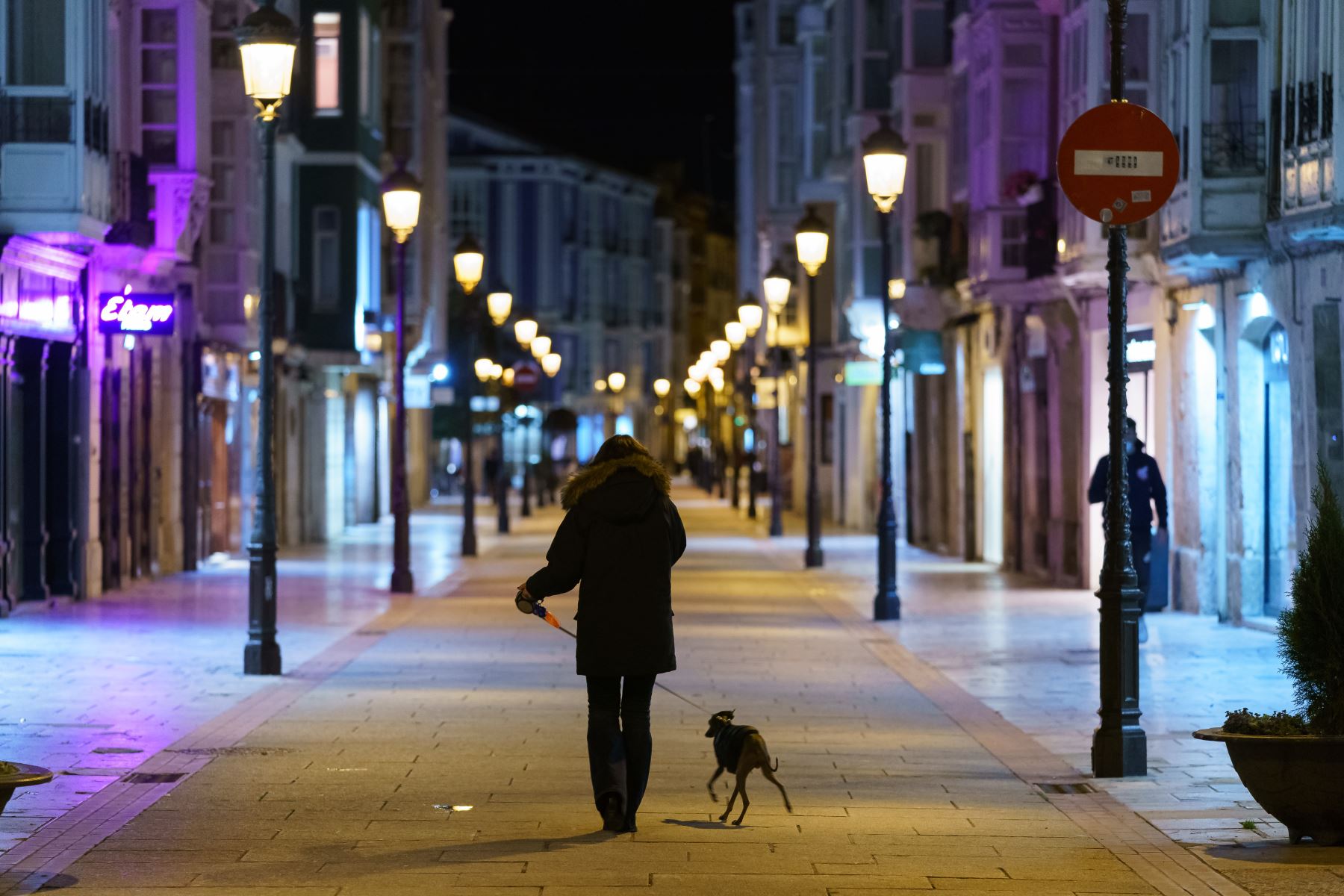 Una mujer pasea a un perro por una calle del centro de Burgos, en la región de Castilla y León, después de que el toque de queda entró en vigor en la localidad, el 24 de octubre de 2020. Foto: AFP