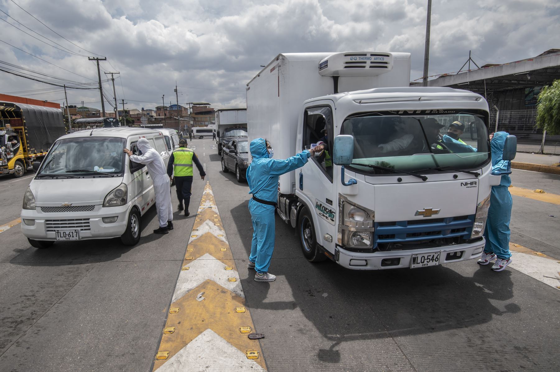 Trabajadores controlan la temperatura corporal de un camionero y su acompañante en medio de la pandemia del nuevo coronavirus, en Bogotá. Foto: AFP
