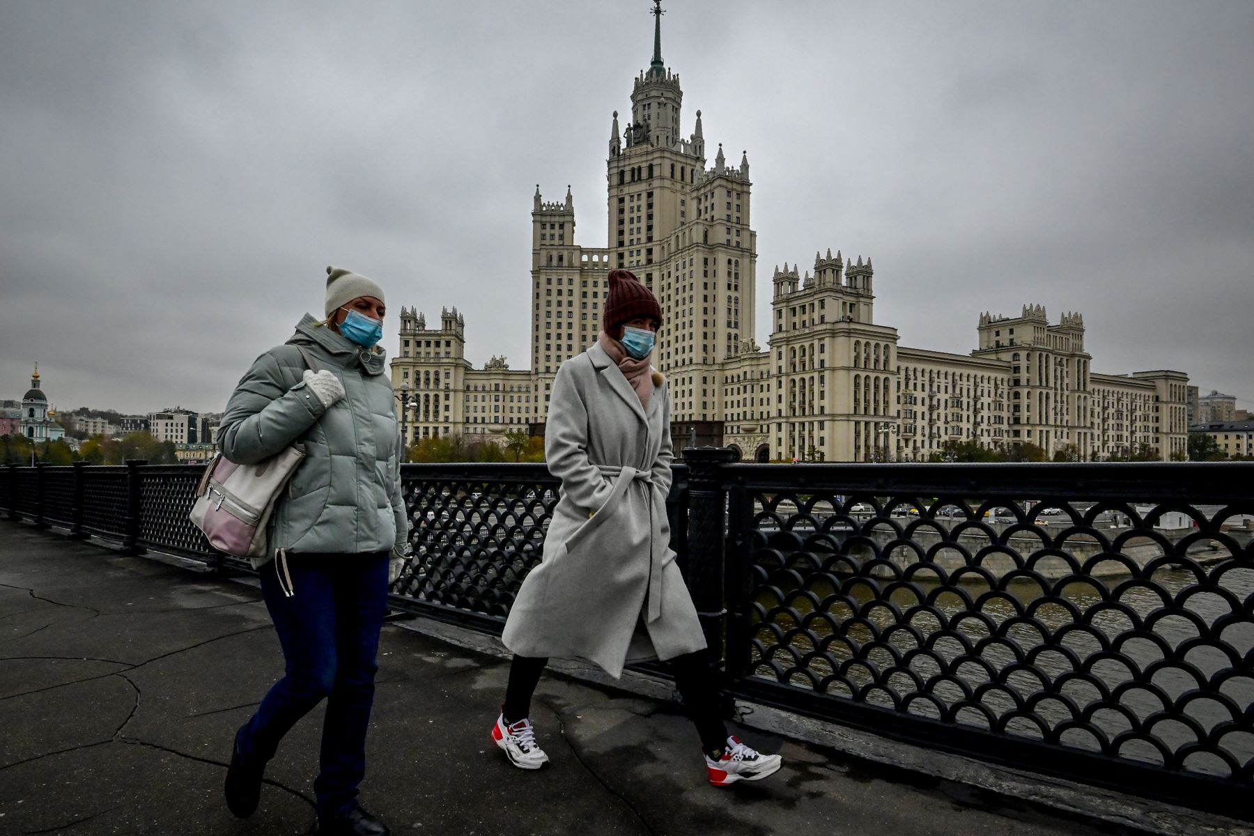 Dos mujeres que usan máscaras faciales para protegerse contra la enfermedad del coronavirus caminan por un puente en el centro de Moscú. Foto: AFP