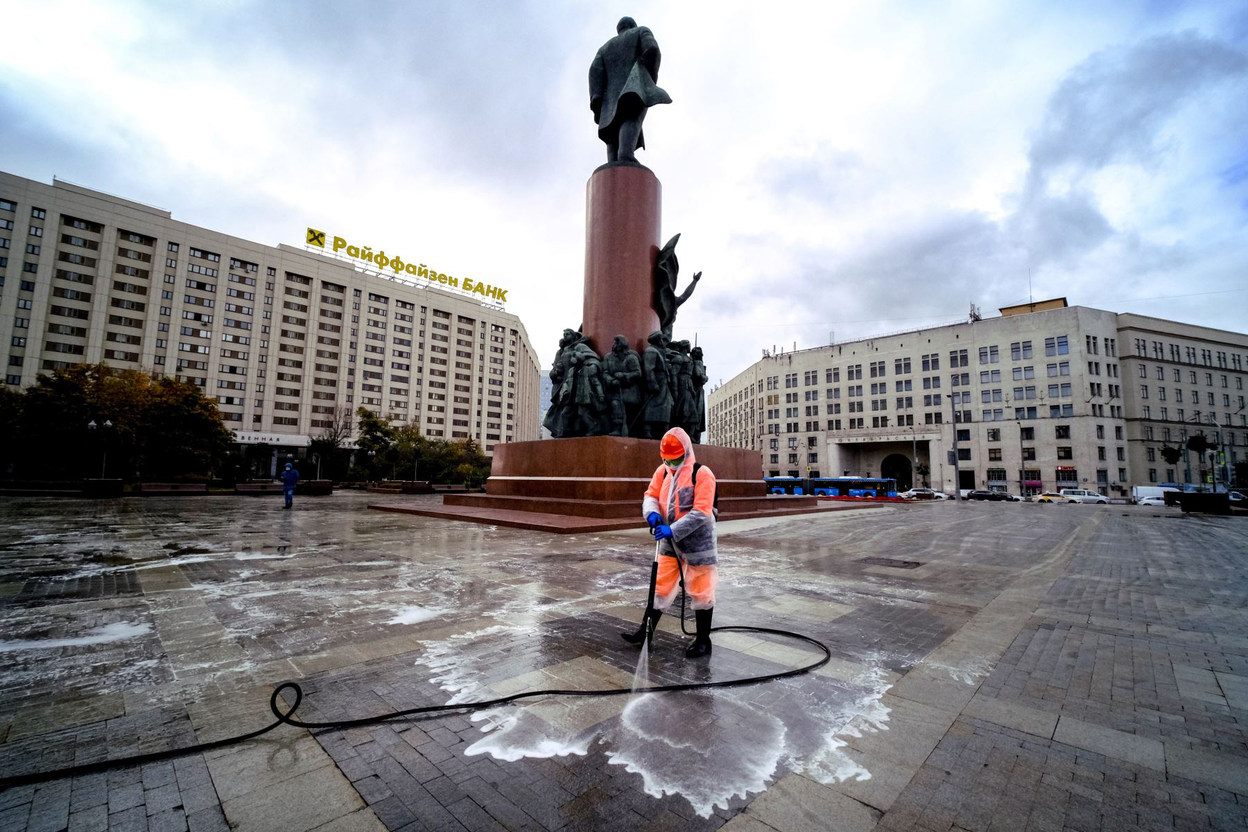 Un trabajador municipal que usa una mascarilla y un traje protector para protegerse contra la enfermedad del coronavirus desinfecta una plaza cerca del monumento a Lenin, en el centro de Moscú. Foto: AFP