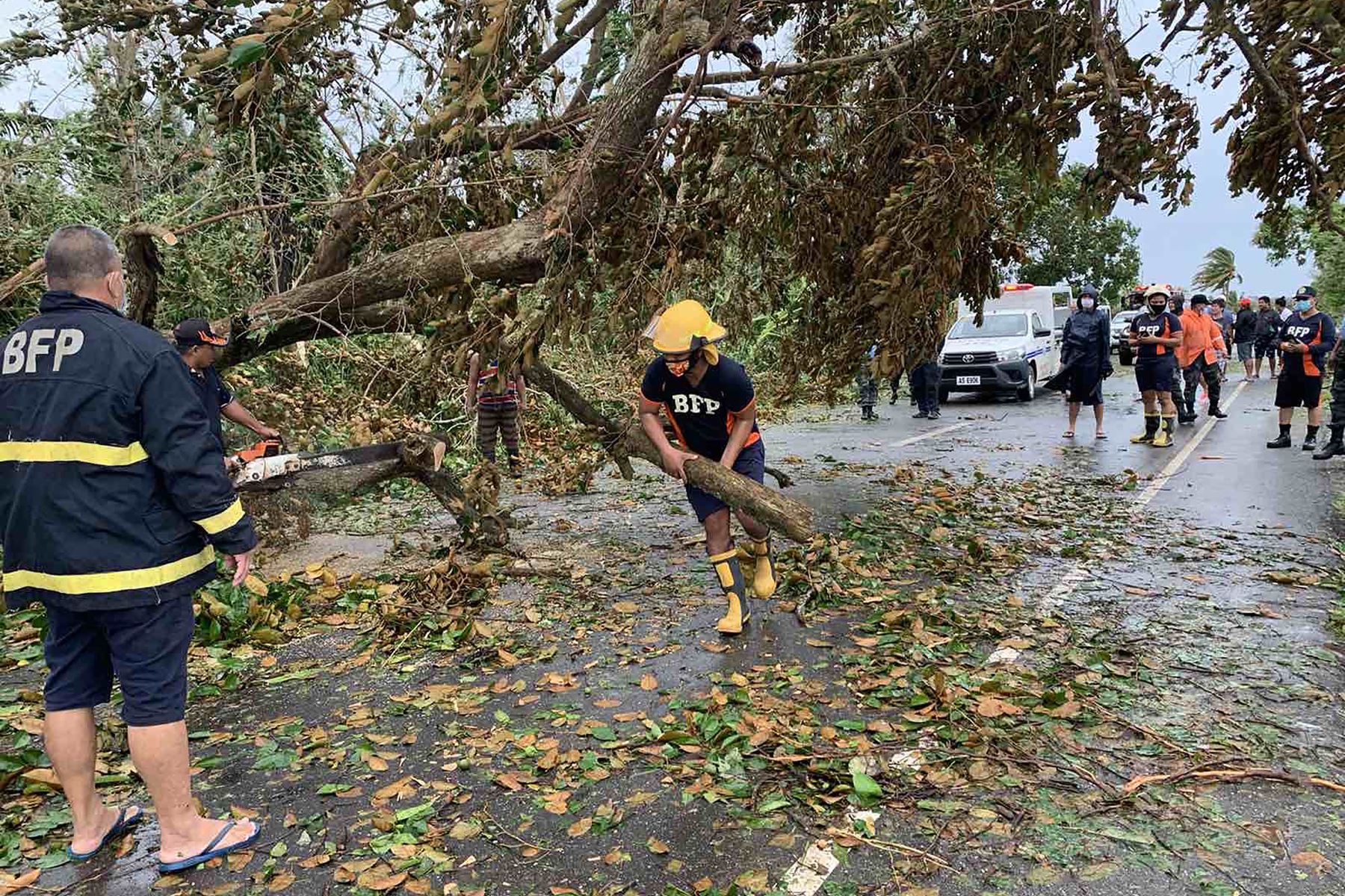 Personal de la oficina de bomberos intenta retirar un árbol caído que bloquea una carretera después que la tormenta tropical Molave ​​azotara la ciudad de Pola, provincia de Mindoro Oriental, en Filipinas. Foto: AFP