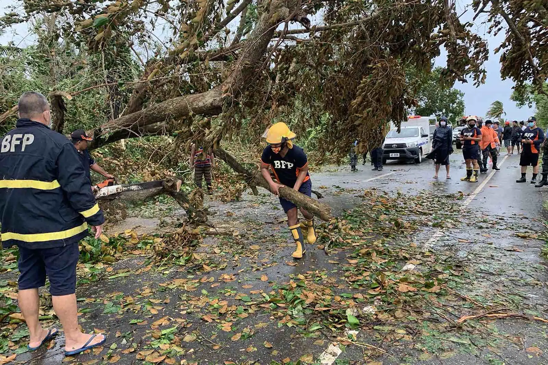 Personal de la oficina de bomberos intenta retirar un árbol caído que bloquea una carretera después que la tormenta tropical Molave ​​azotara la ciudad de Pola, provincia de Mindoro Oriental, en Filipinas. Foto: AFP
