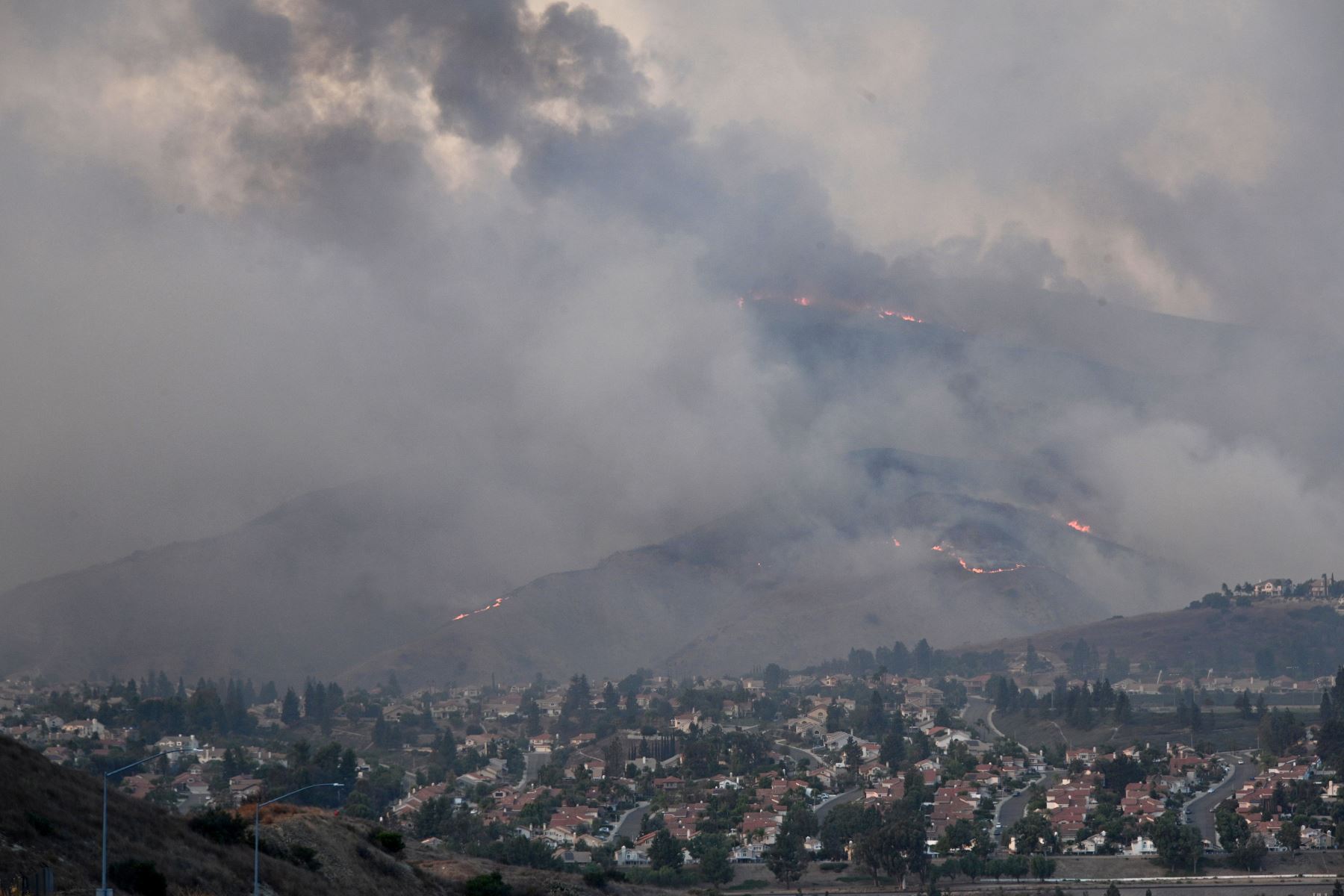 El fuego y el humo del Blue Ridge Fire se elevan sobre las casas en Yorba Linda, California. Foto: AFP