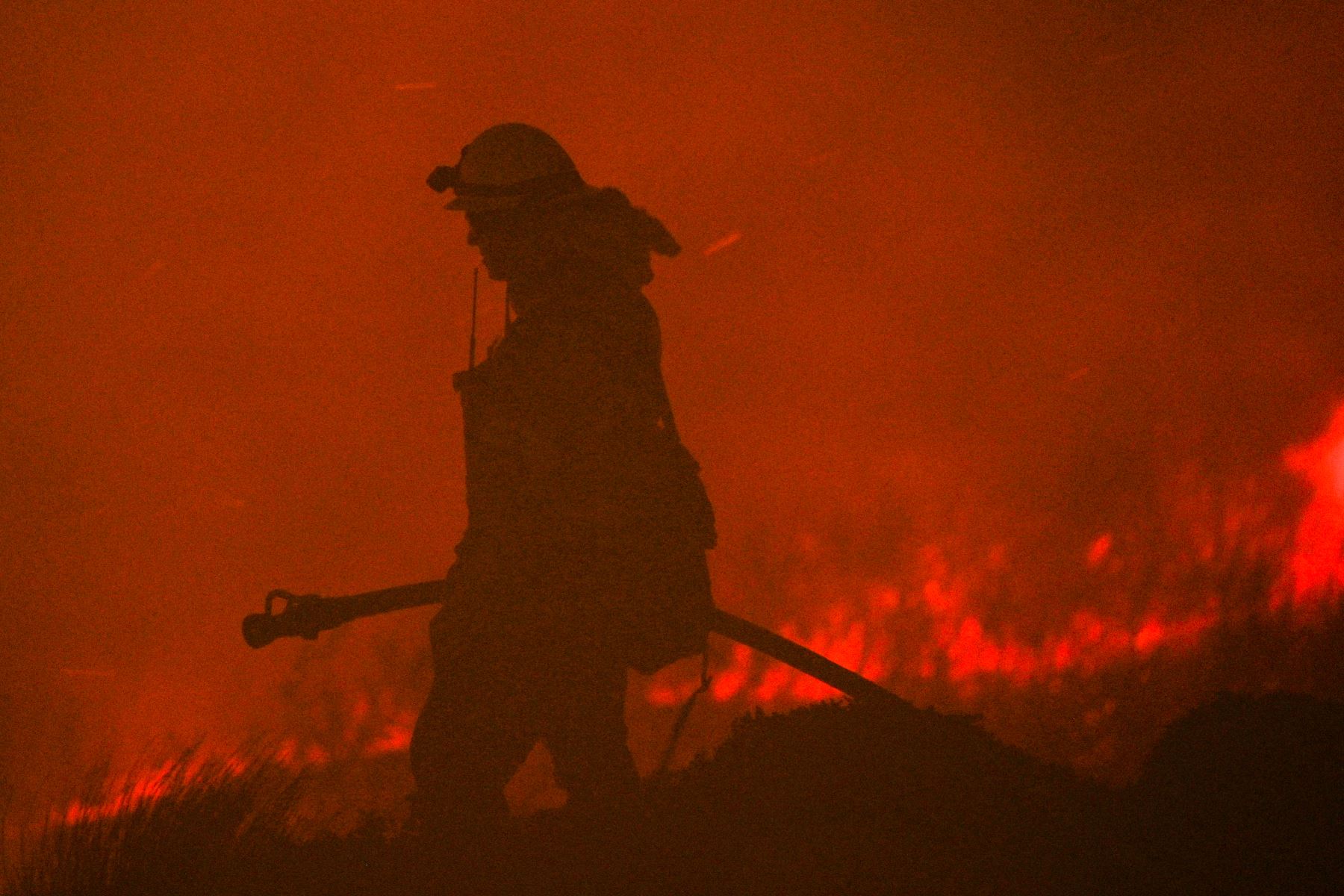 Un bombero sostiene una manguera mientras el incendio Blue Ridge continúa ardiendo en Yorba Linda, California. Foto: AFP
