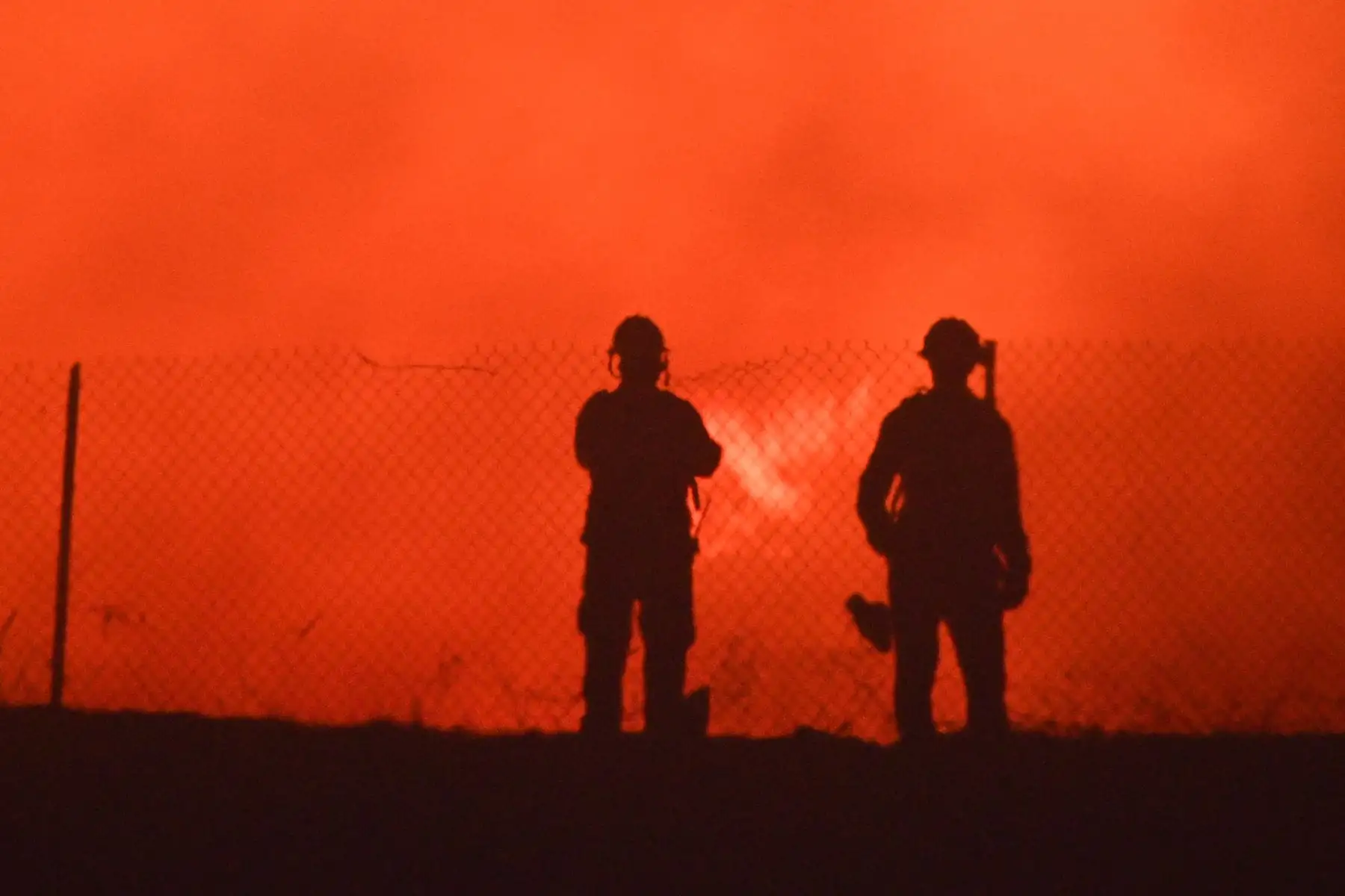Los bomberos se ubican en un área residencial y monitorean las llamas que trepan por una cresta hacia las casas en Yorba Linda, California. Foto: AFP