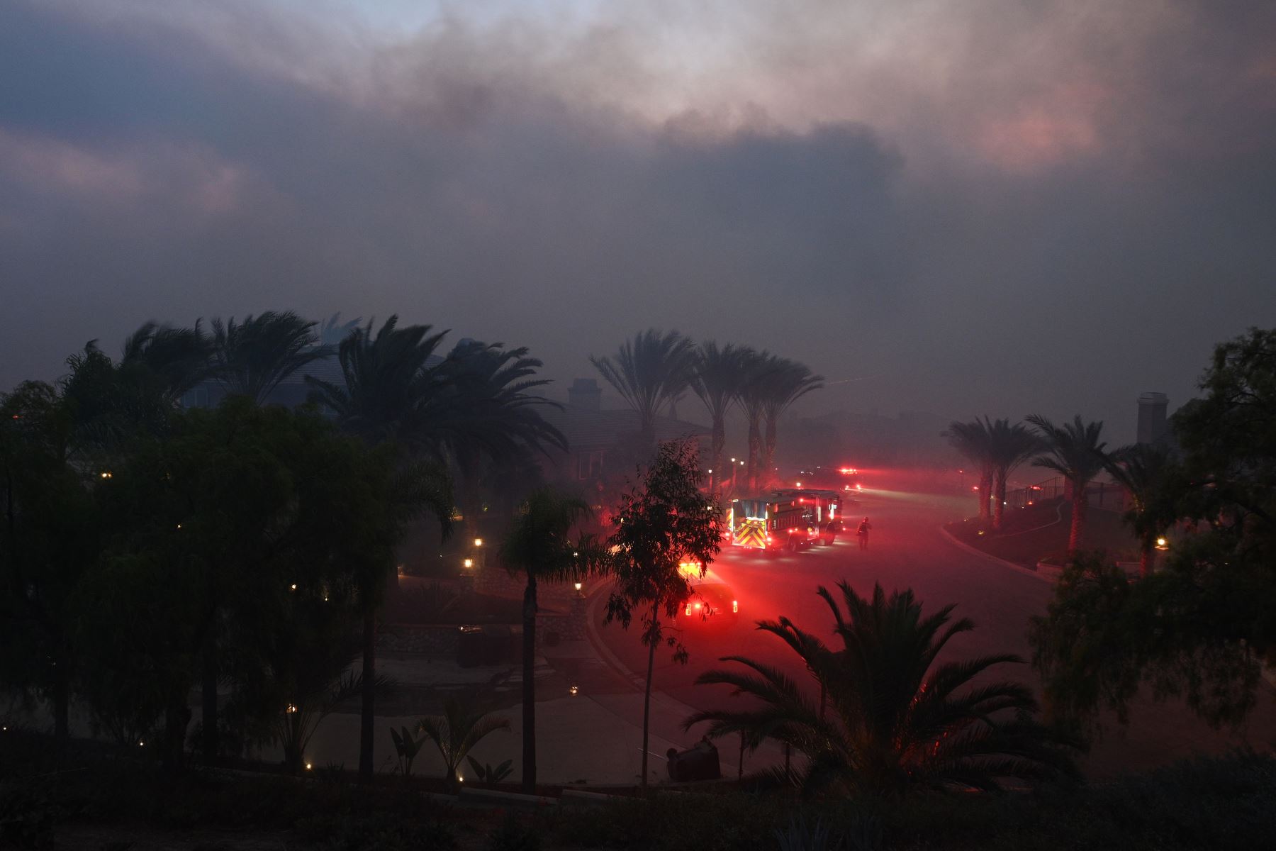 Los bomberos se ubican en un área residencial y monitorean las llamas que trepan por una cresta hacia las casas en Yorba Linda, California.