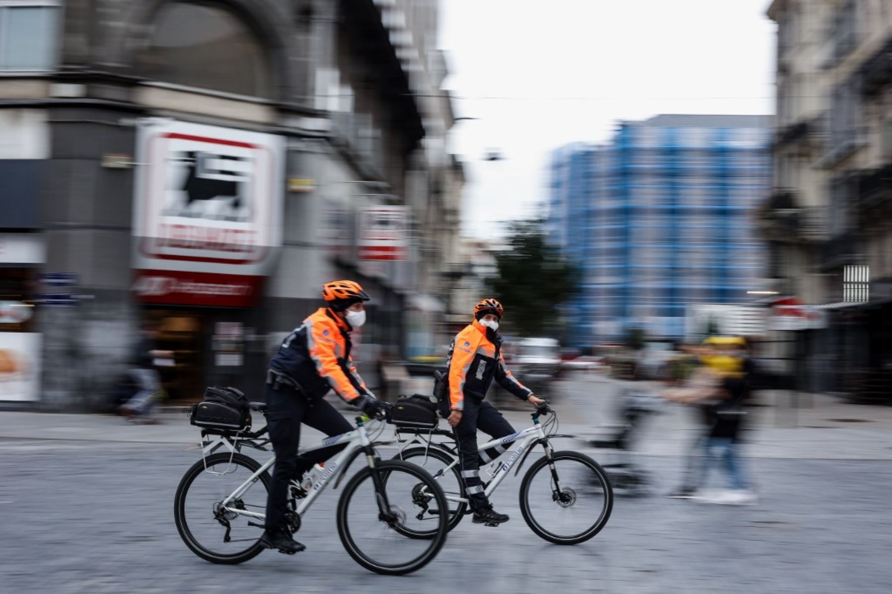 Agentes de policía con máscaras protectoras patrullan en bicicletas en Bruselas, en el día de implementación de nuevas medidas sanitarias destinadas a frenar la propagación del brote de Covid-19. Foto: AFP