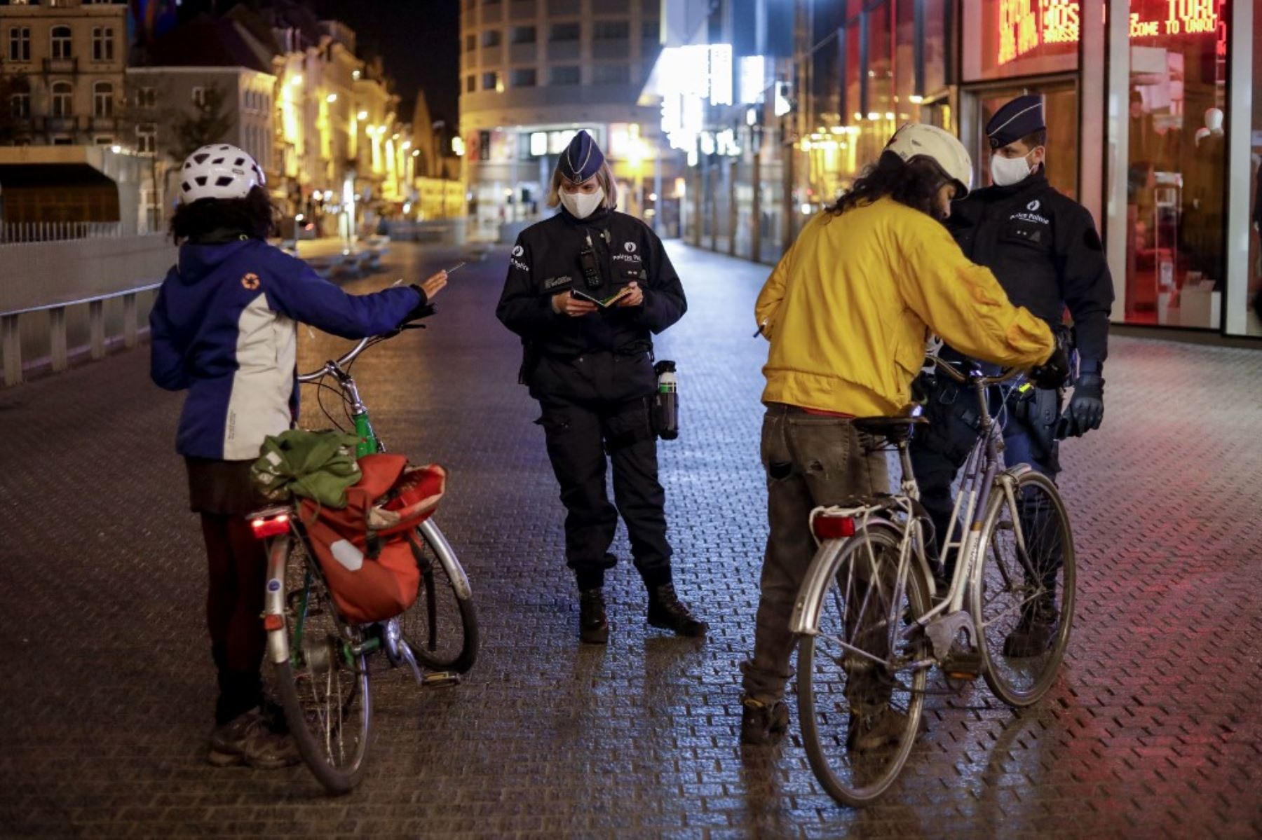 Los agentes de policía que llevan máscaras protectoras controlan a las personas que andan en bicicleta mientras patrullan al inicio del toque de queda en Bruselas como medida contra la propagación de la pandemia COVID-19 causada por el nuevo coronavirus. Foto: AFP