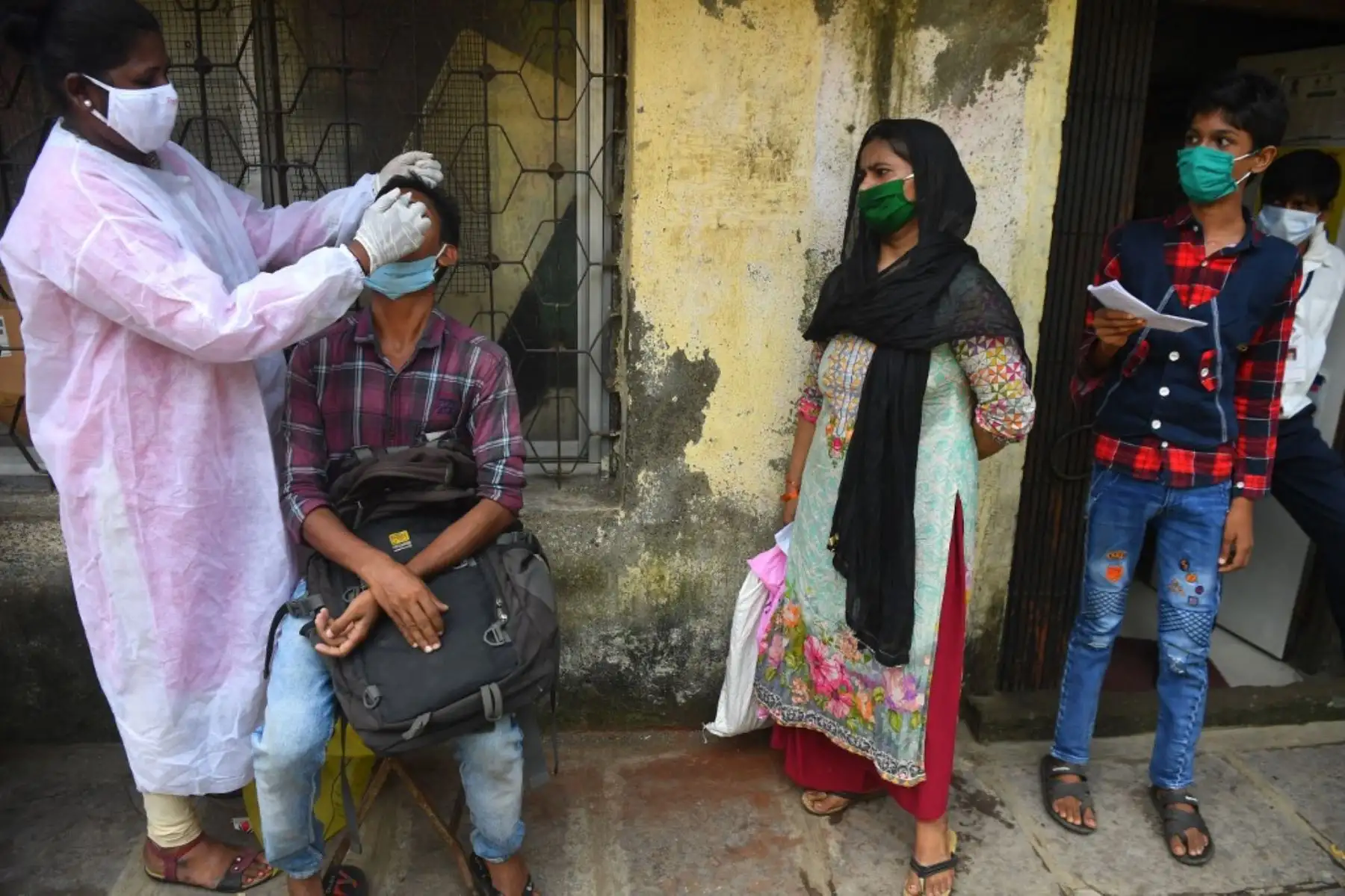 Un trabajador de la salud, toma una muestra de hisopo de un residente durante una prueba de detección del coronavirus en Mumba. Foto: AFP