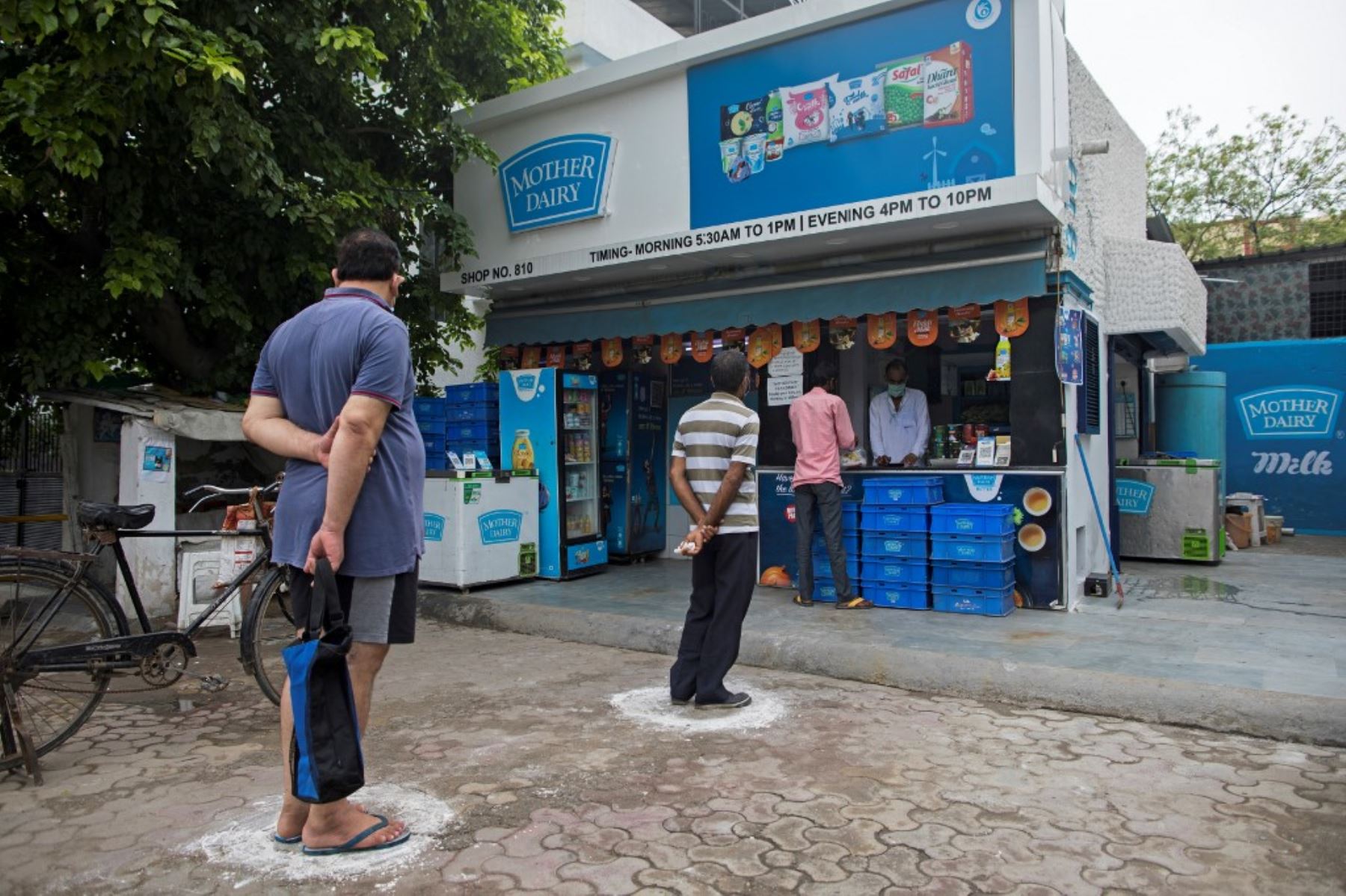 Los clientes se paran en círculos marcados en el suelo para mantener el distanciamiento social mientras hacen cola en una tienda Mother Dairy, como medida preventiva contra la propagación del coronavirus . Foto:AFP
